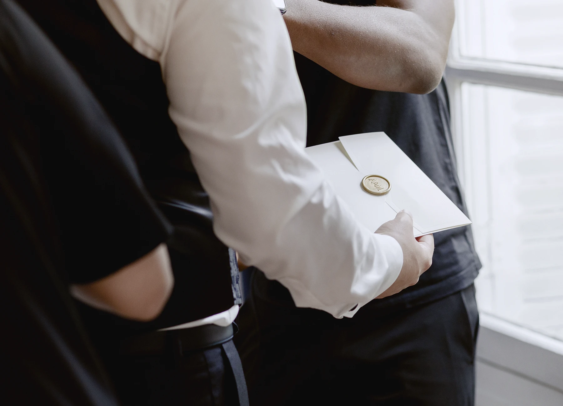 Main du marié tenant une lettre lors des préparatifs du mariage au château. Photo par Laurène Zabary.