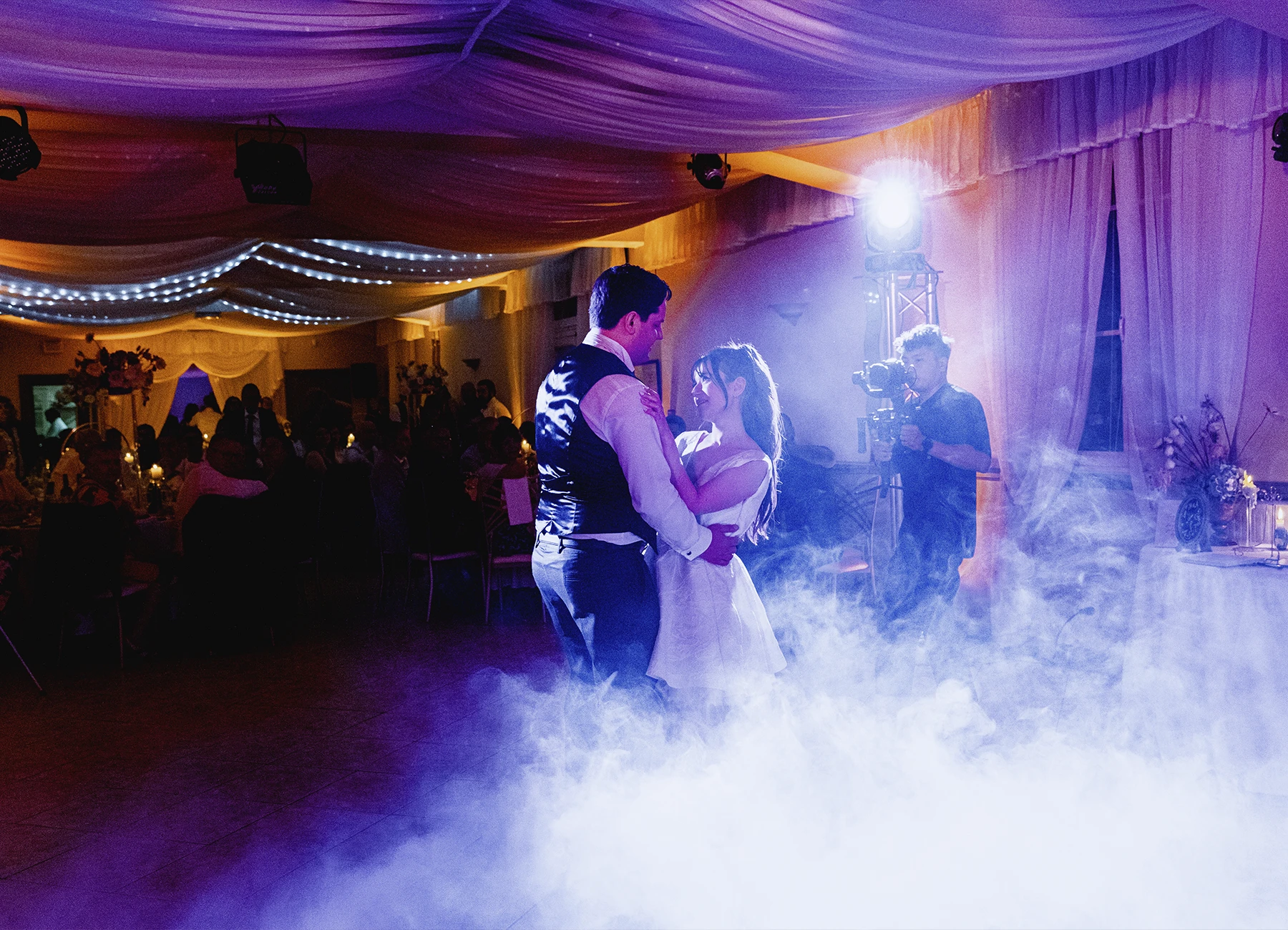 Mariée regardant son marié sous des lumières violettes et jaunes, ouverture du bal à Quesmy, photographie par Laurène Zabary