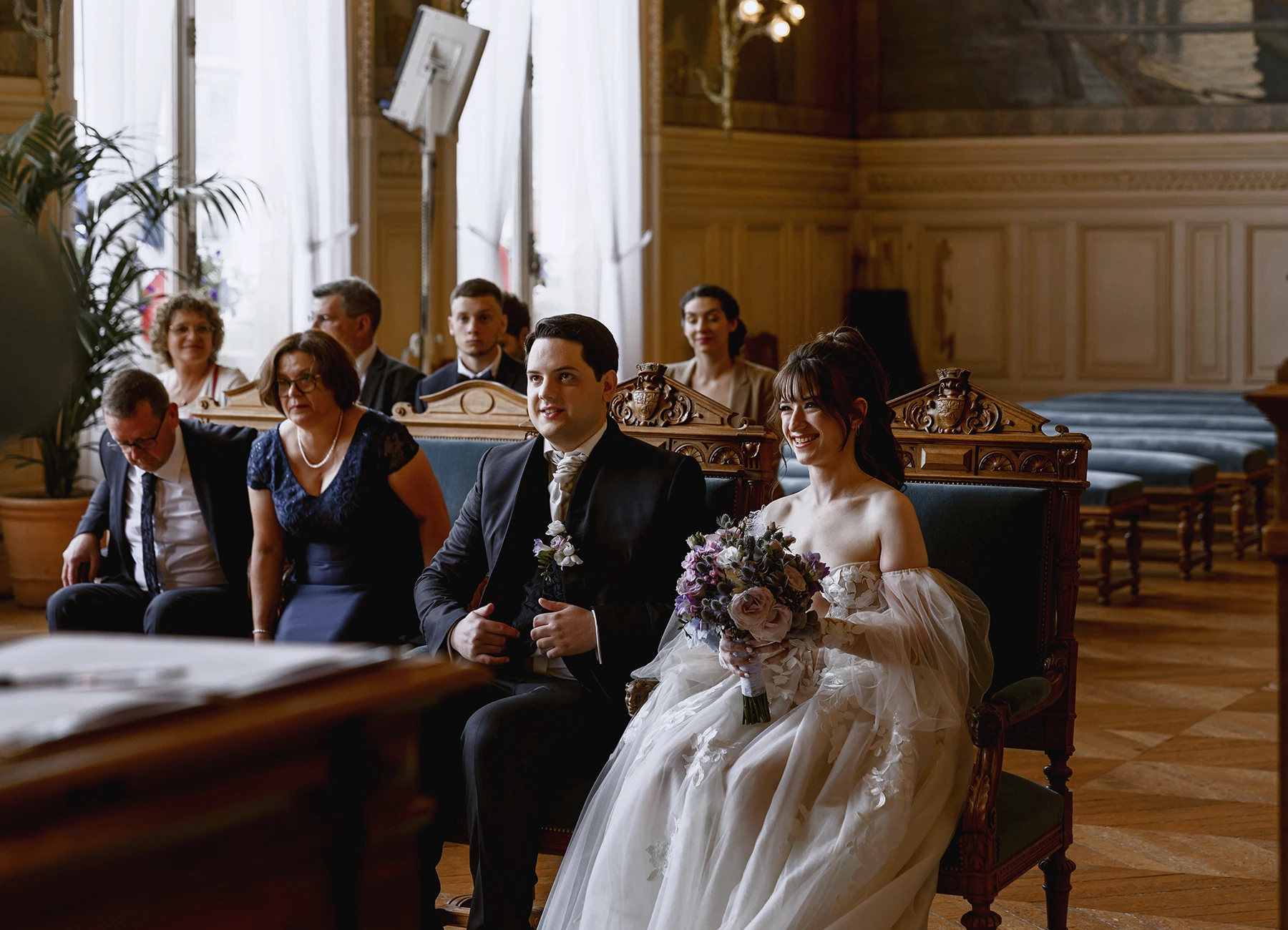 Les mariés souriants assis côte à côte à la mairie d'Asnières-sur-Seine. Photo par Laurène Zabary.
