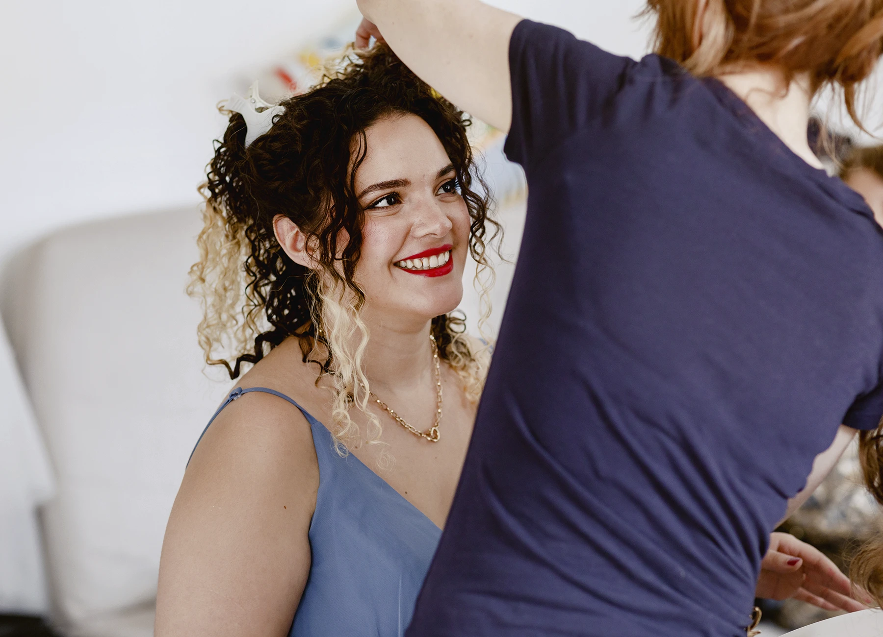 Témoin de la mariée souriant pendant la coiffure avant le mariage. Photo par Laurène Zabary.