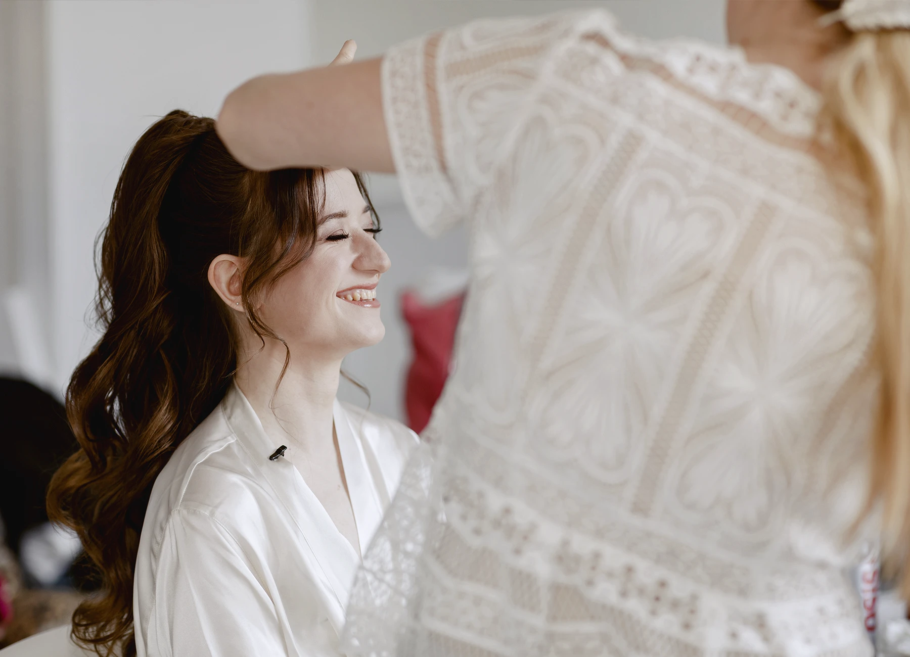 Mariée souriante les yeux fermés pendant la coiffure. Photo par Laurène Zabary.