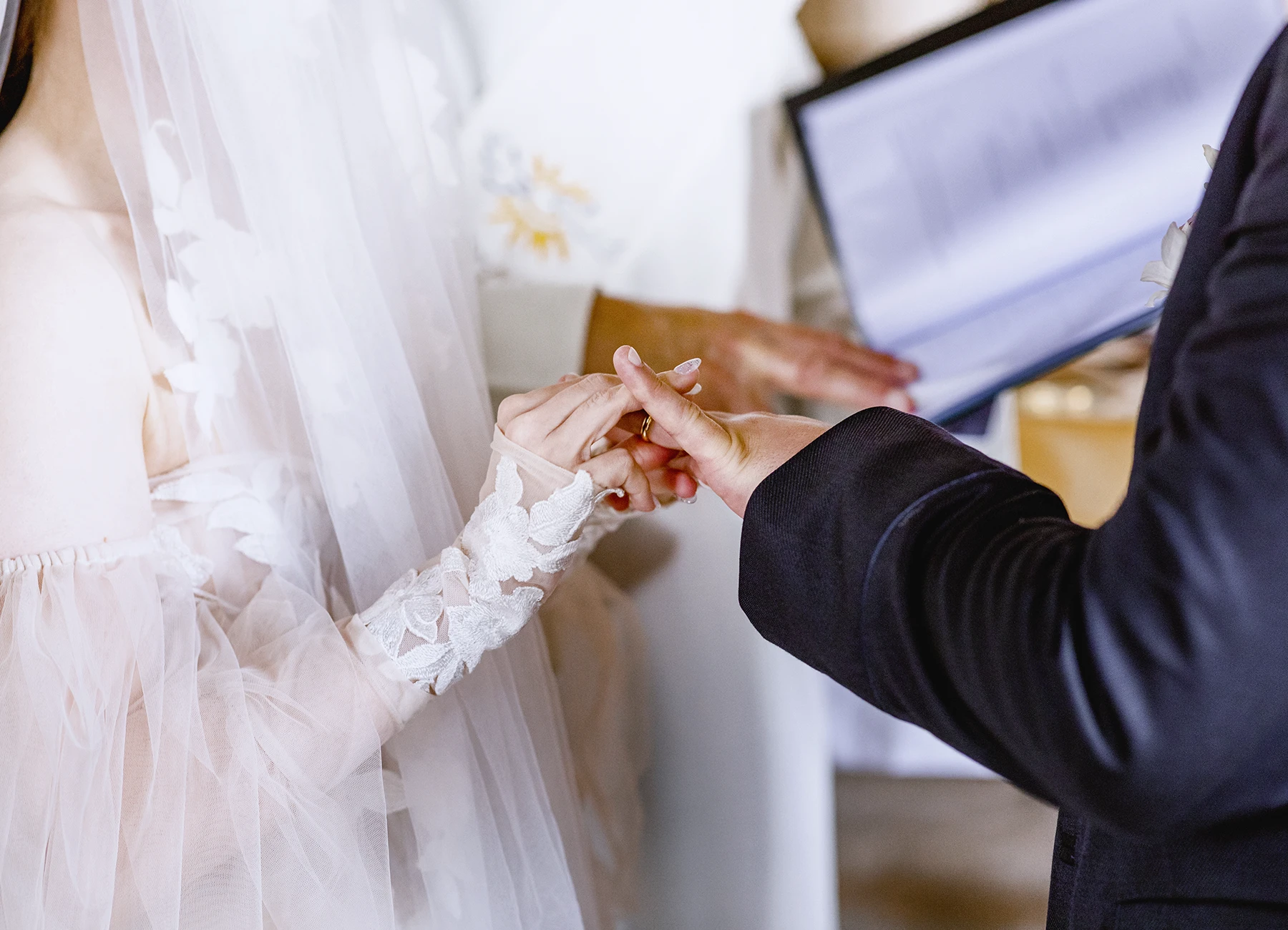 Gros plan sur les mains des mariés échangeant les alliances à l'église de Quesmy. Photo par Laurène Zabary.