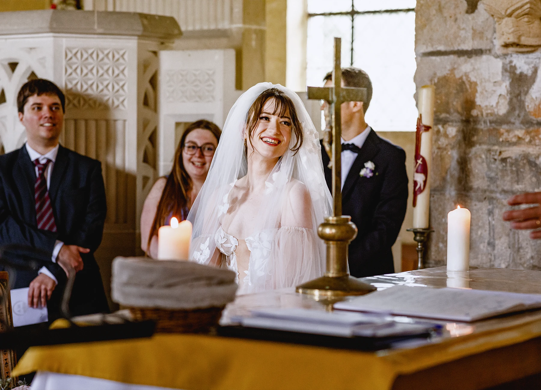 Mariée souriante avec voile relevé à l'église de Quesmy. Photo par Laurène Zabary.