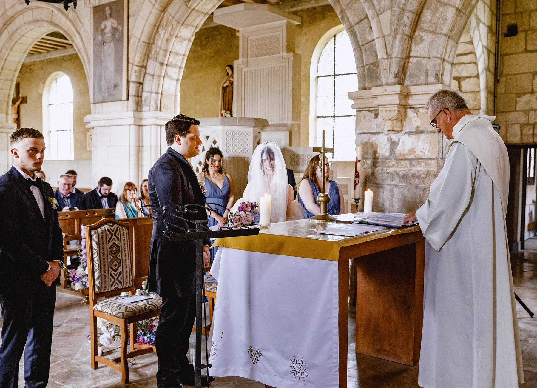 Les mariés se regardant avec amour pendant la cérémonie à l'église de Quesmy. Photo par Laurène Zabary.