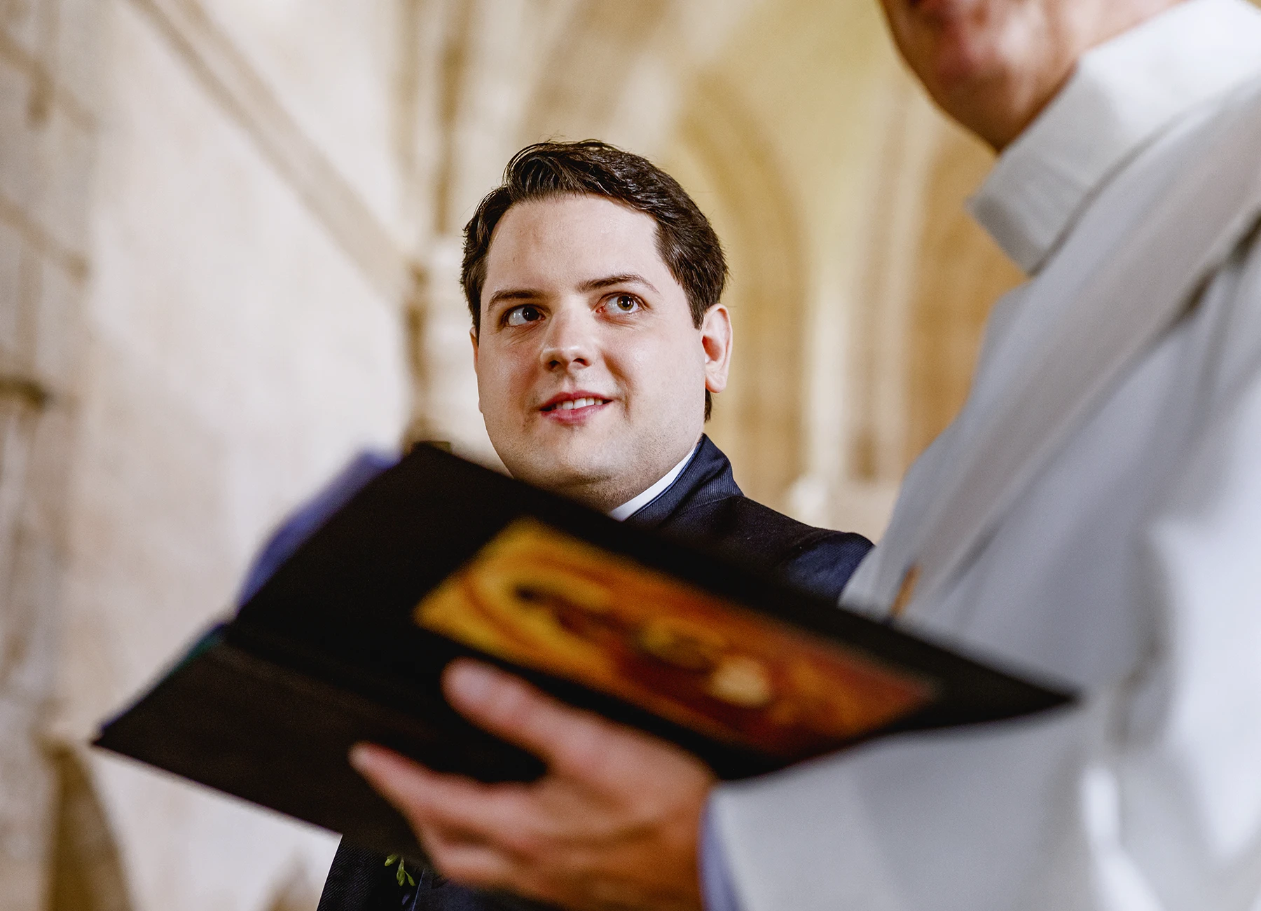 Portrait du marié levant les yeux vers le prêtre à l'église de Quesmy. Photo par Laurène Zabary.