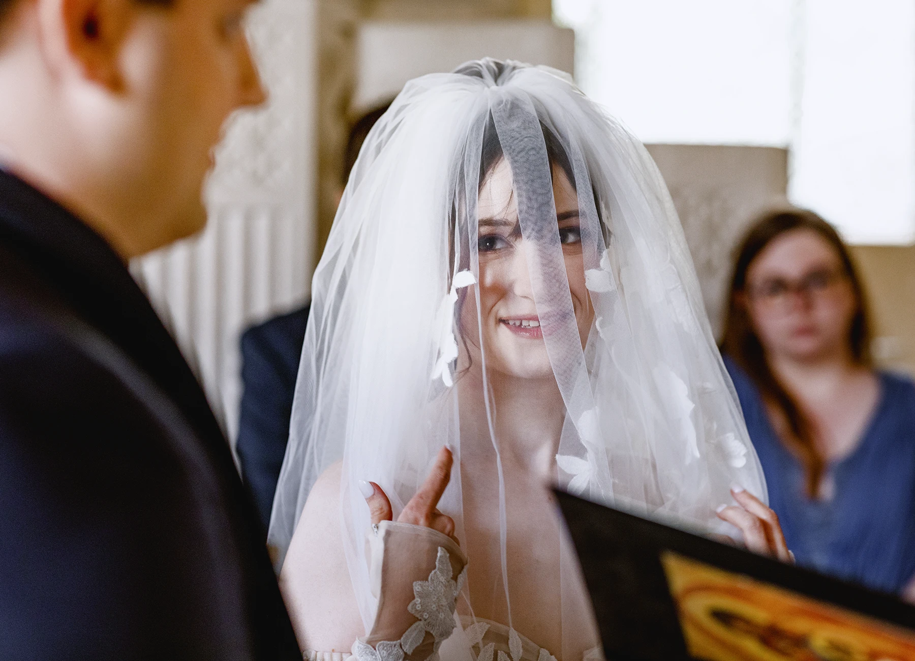Mariée avec son voile regardant le marié à l'église de Quesmy. Photo par Laurène Zabary.