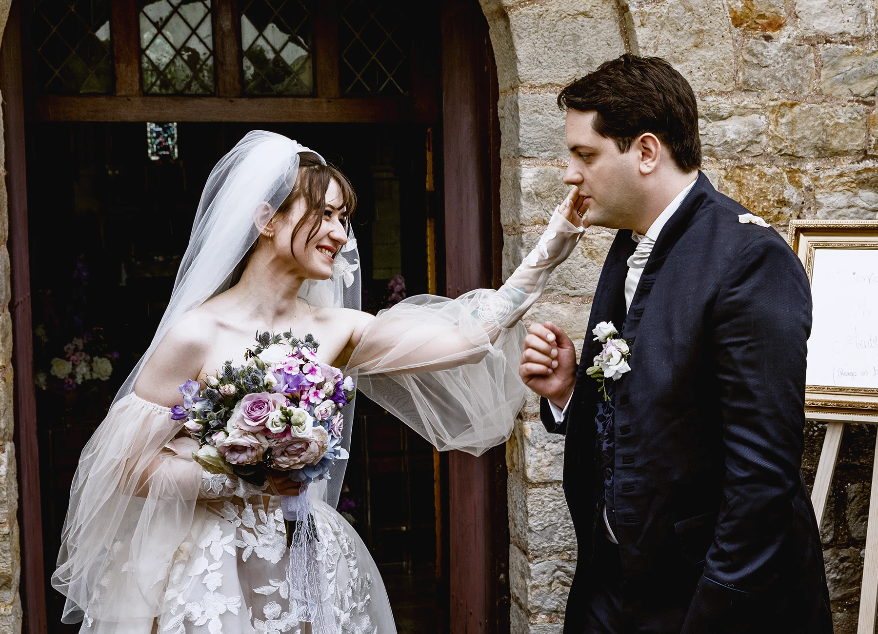 Mariée caressant la joue du marié à la sortie de l'église de Quesmy. Photo par Laurène Zabary.