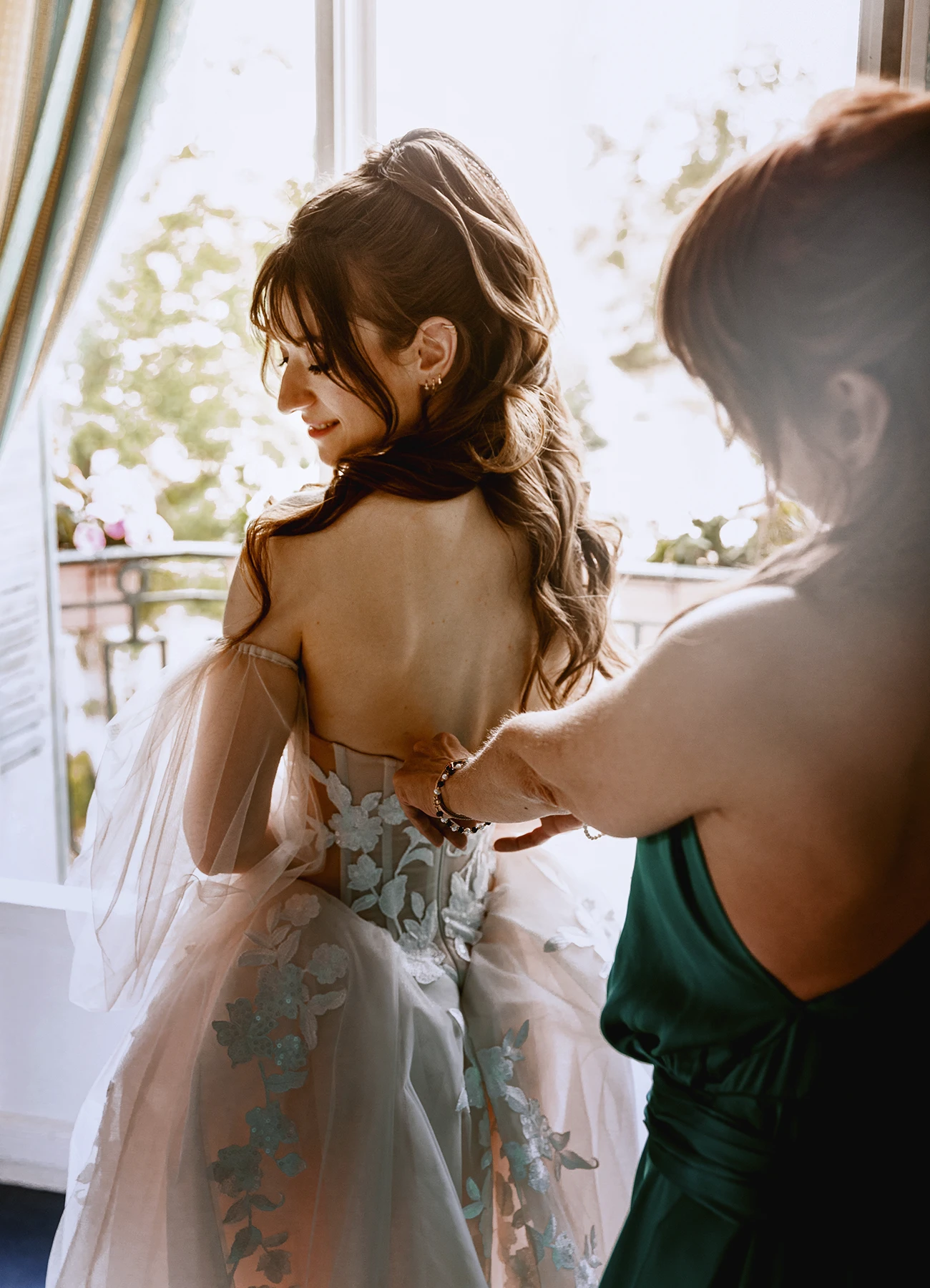 Plan serré de la mère ajustant le corset de la mariée. Photo par Laurène Zabary.