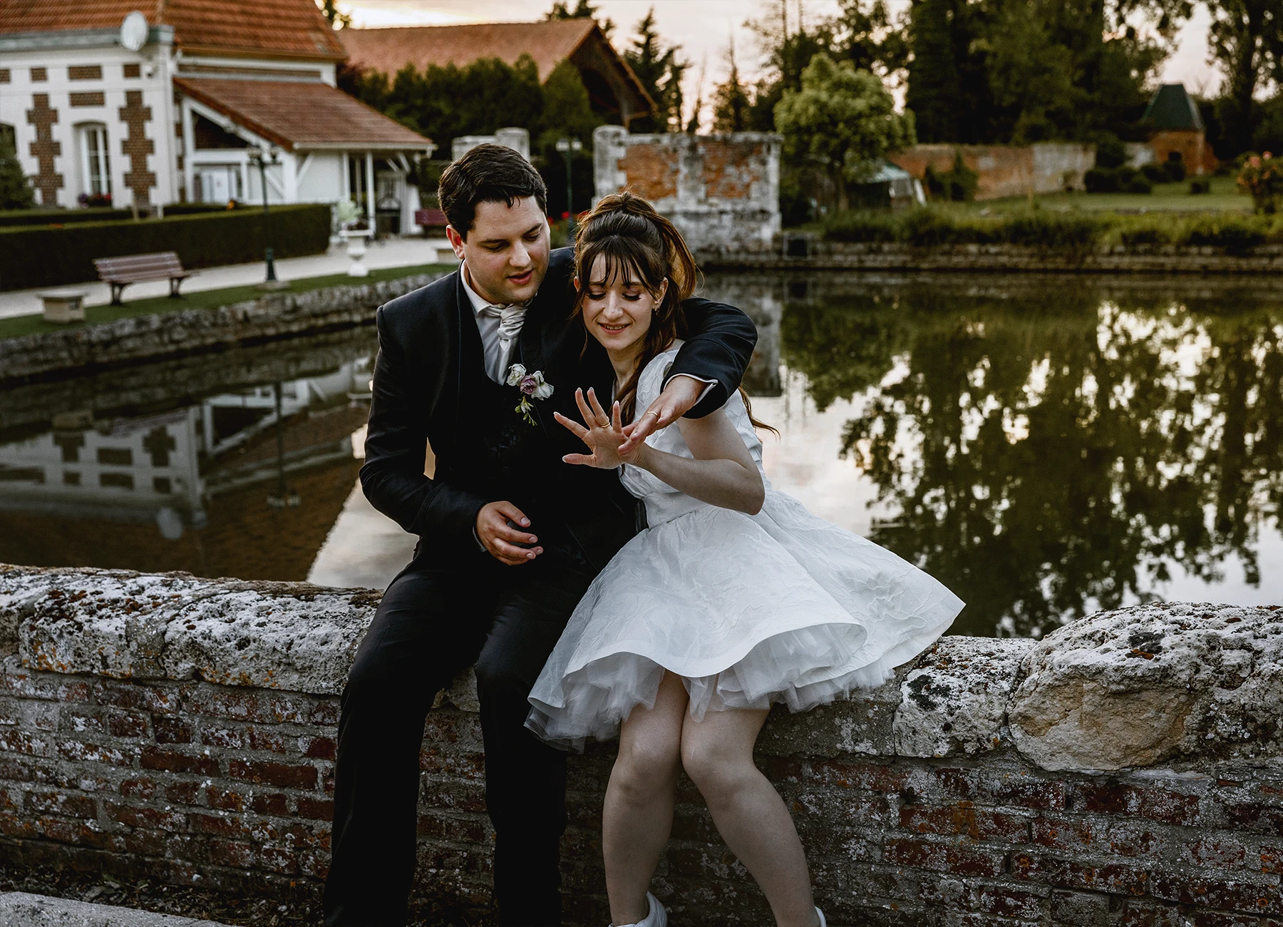 Mariée regardant son alliance, assise sur une margelle au château de Quesmy, golden hour, photo par Laurène Zabary