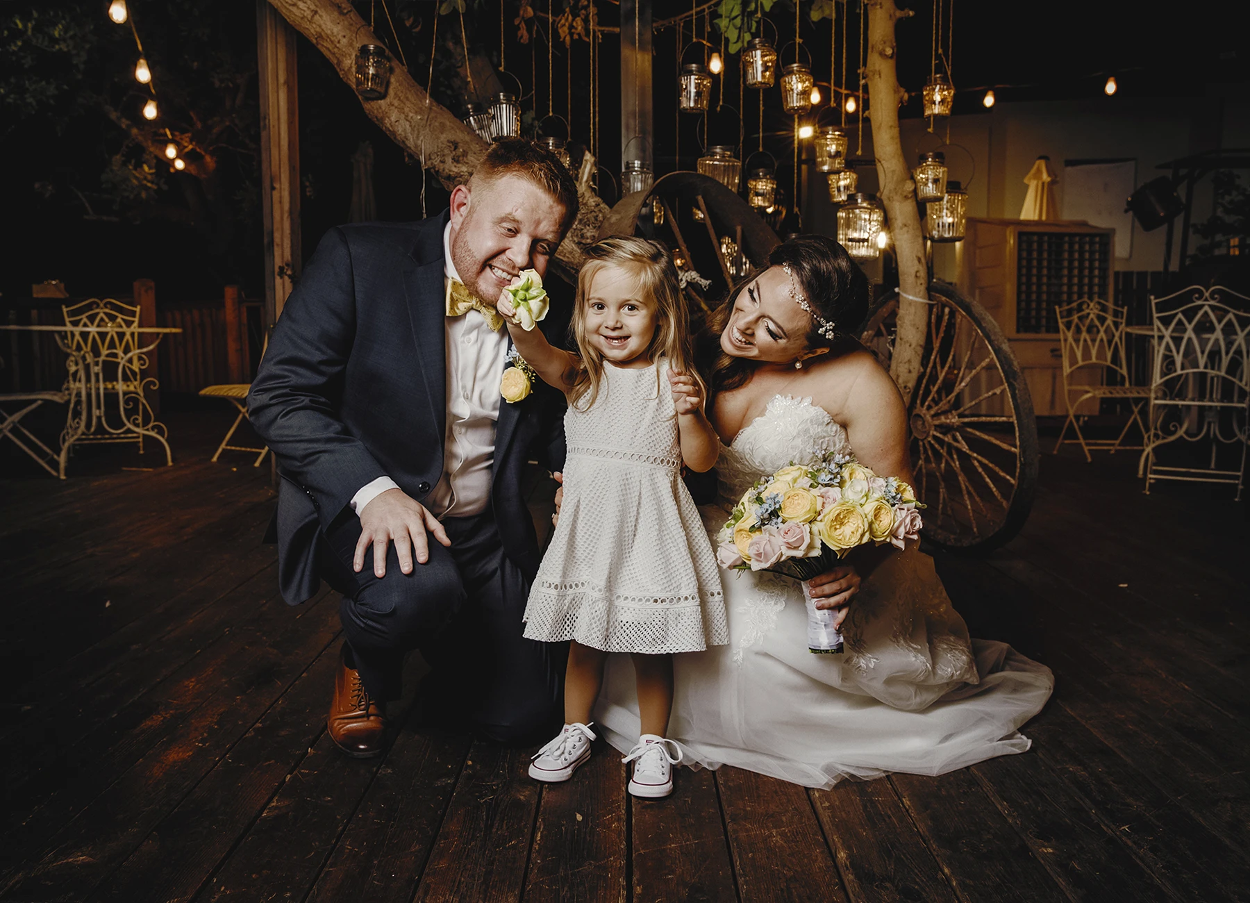 Petite fille en robe blanche jouant avec une fleur du bouquet de la mariée - Laurène Zabary
