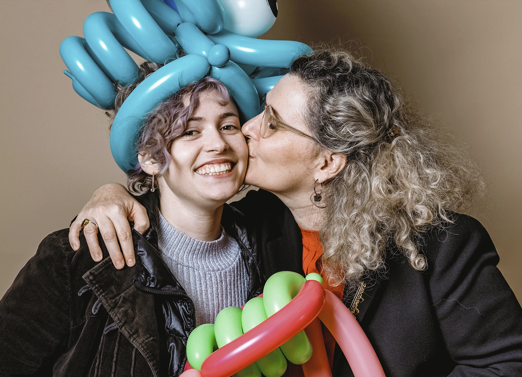 Deux femmes portant des couronnes en ballons, l'une embrassant l'autre sur la joue lors de la soirée de mariage - Laurène Zabary