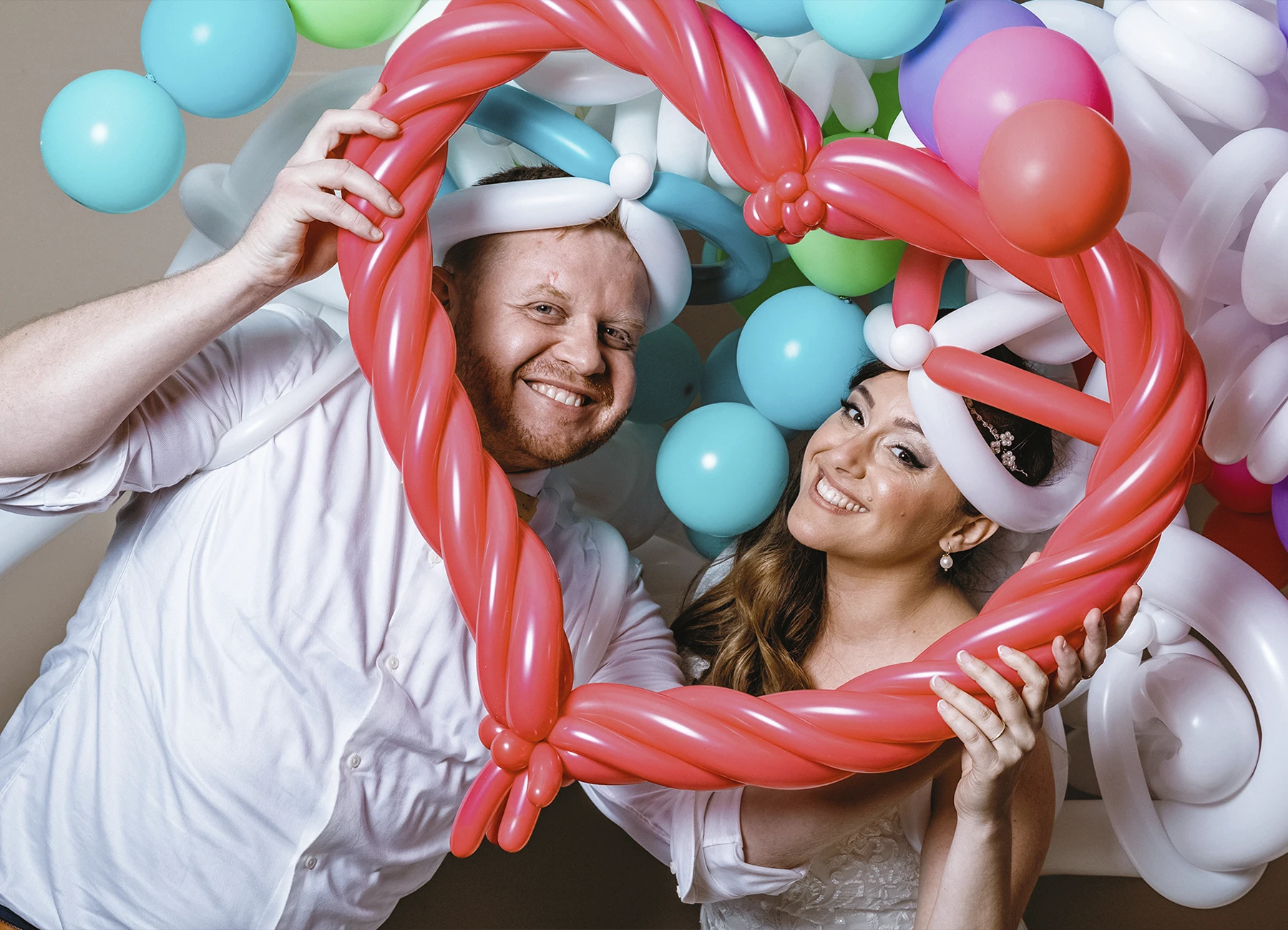 Les mariés posant entourés de ballons colorés pendant la soirée de mariage - Laurène Zabary