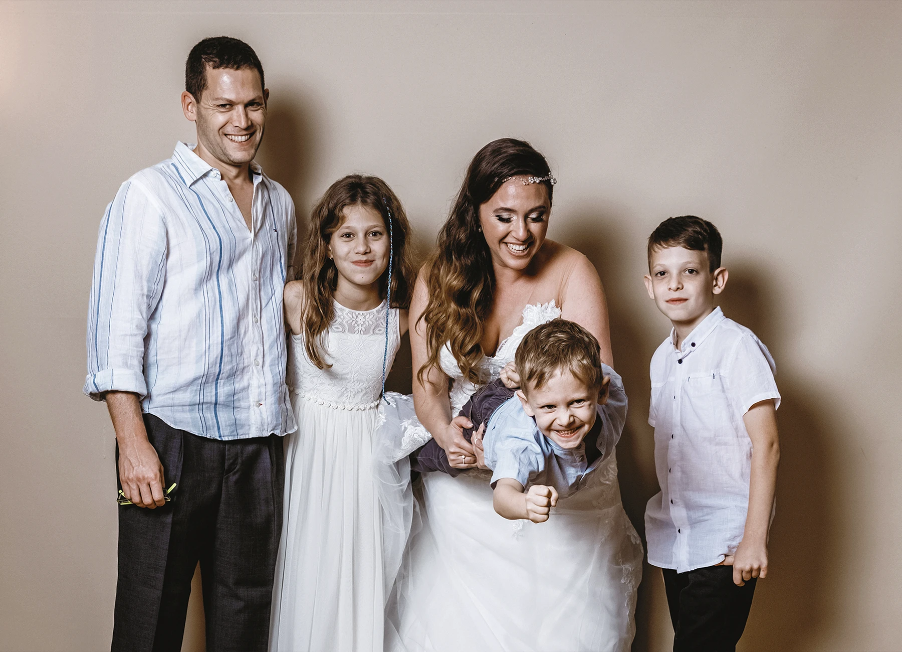 Mariée tenant un petit garçon dans ses bras entourée d'enfants lors de la soirée de mariage - Laurène Zabary