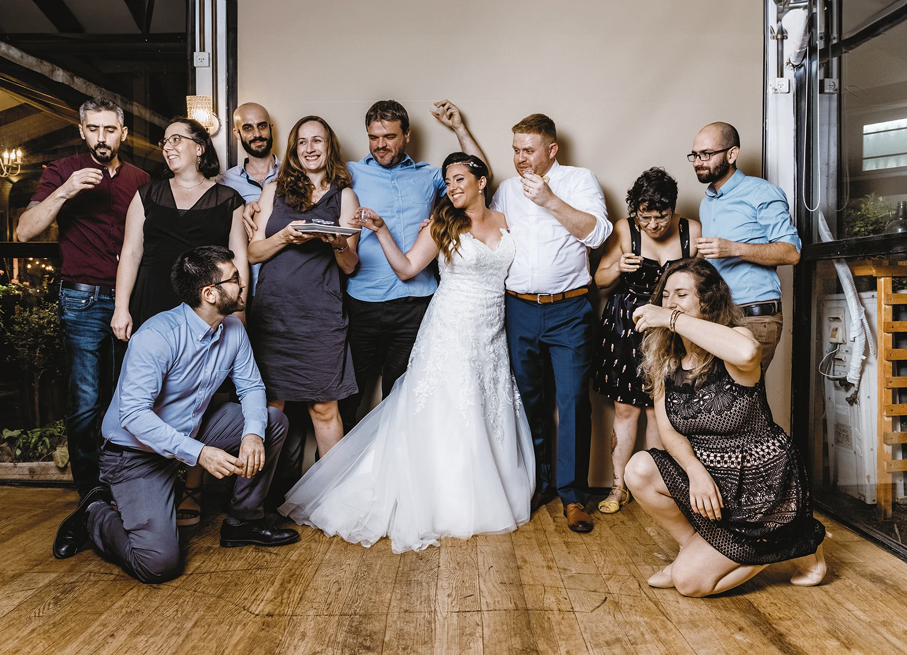 Mariés posant avec des invités en soirée de mariage sur fond uni beige - Laurène Zabary