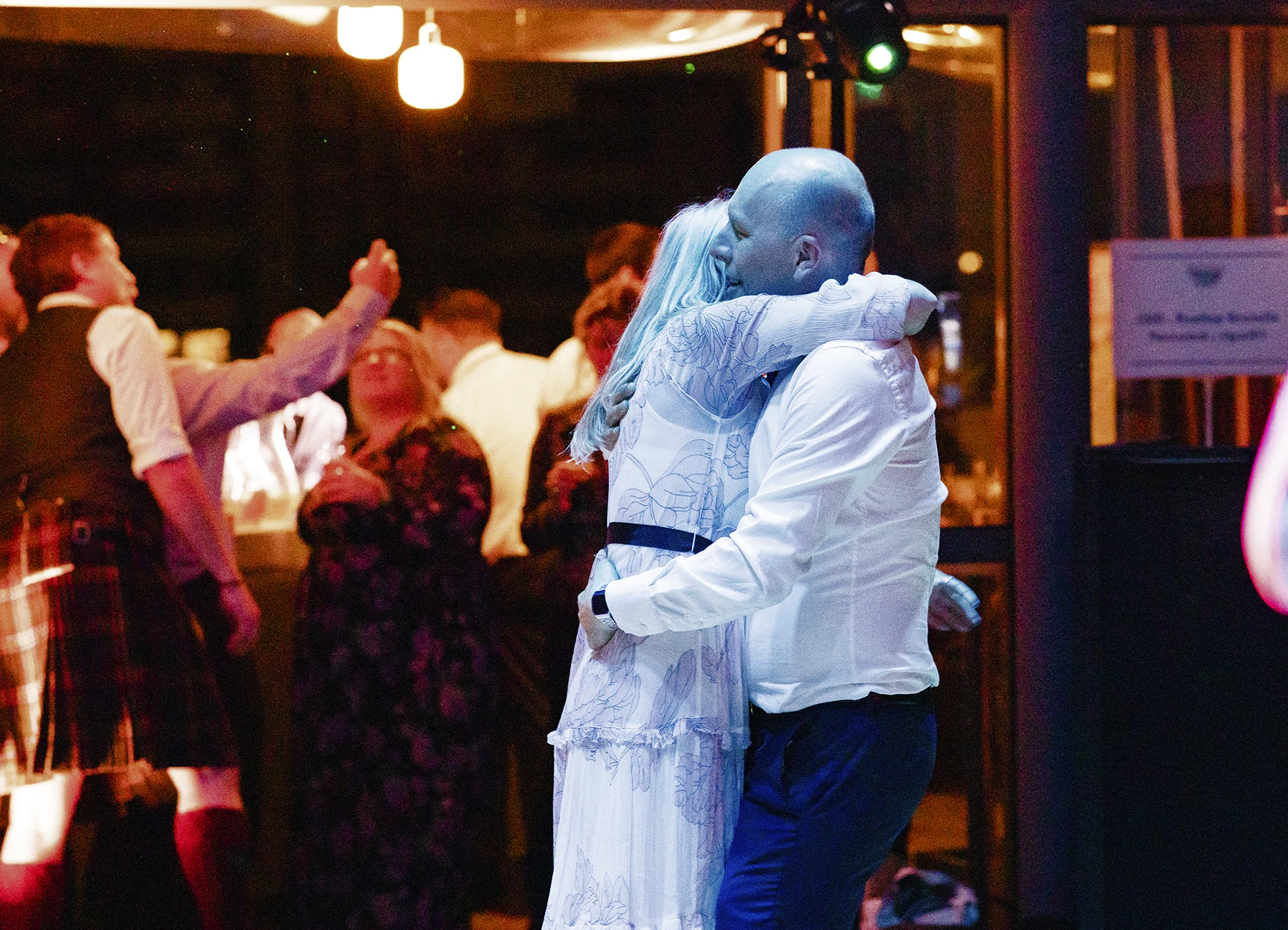 Un couple s'enlace tendrement sous les lumières bleues de la soirée dansante à Paris, capturés par Laurène Zabary, photographe de mariage.