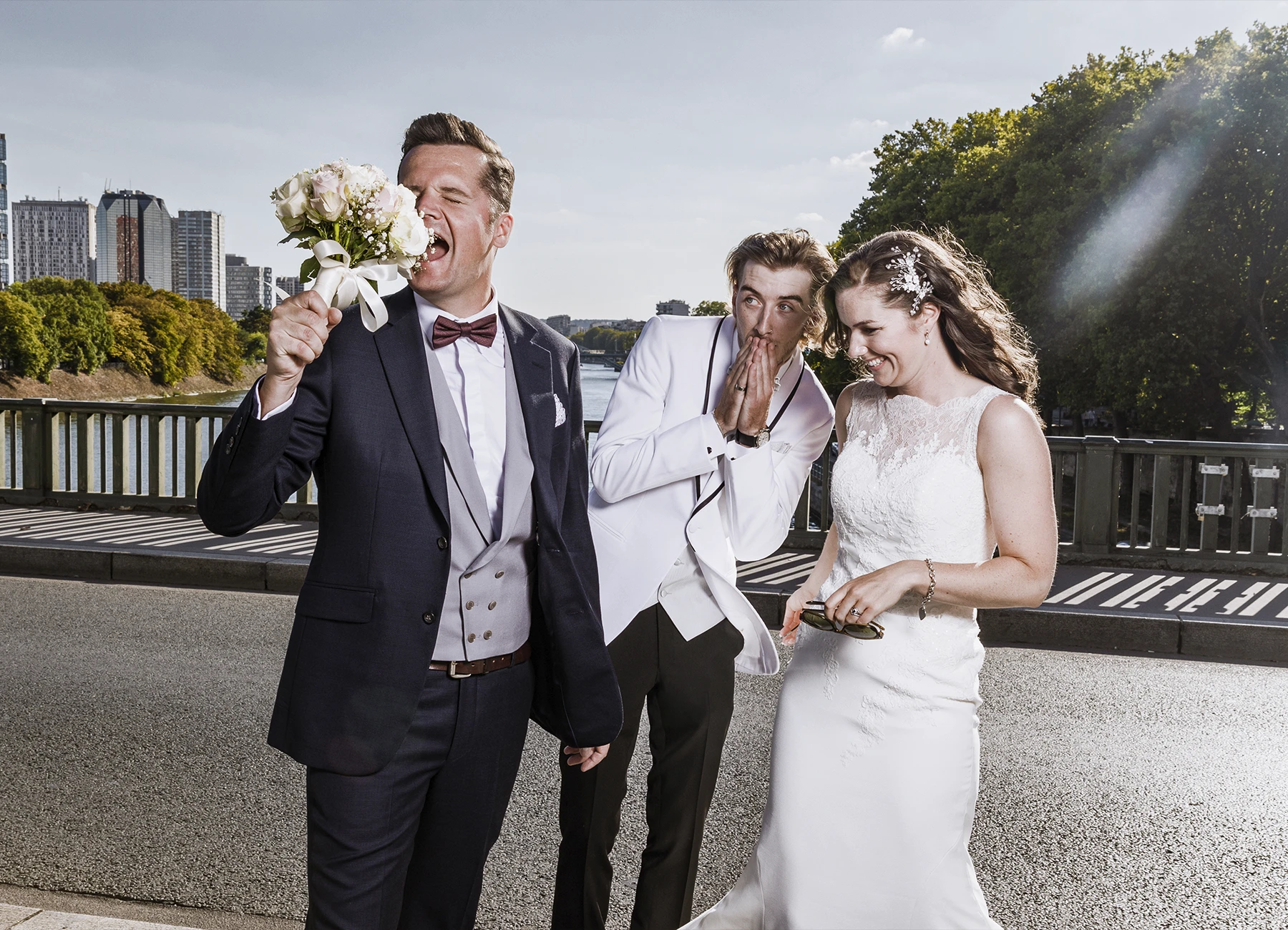 Marié faisant mine de manger le bouquet de fleurs, avec la mariée et son frère, sur le pont Bir Hakeim à Paris, capturé par Laurène Zabary.