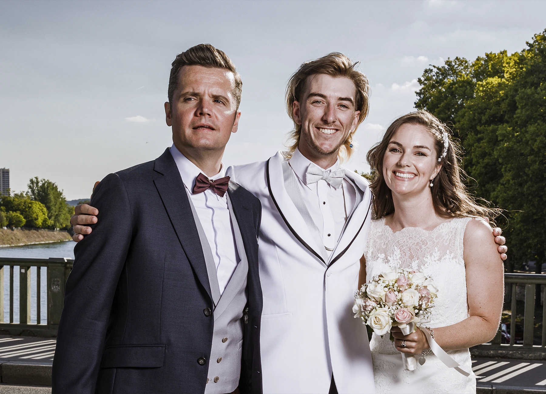 Mariés et frère de la mariée souriant pour une photo classique sur le pont Bir Hakeim à Paris, capturés par Laurène Zabary