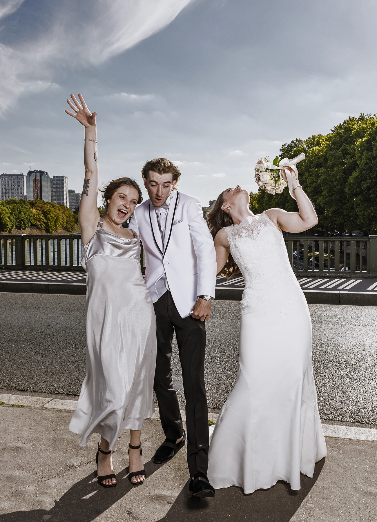 Mariée utilisant son bouquet comme micro pour une photo de groupe amusante sur le pont Bir Hakeim à Paris, capturée par Laurène Zabary