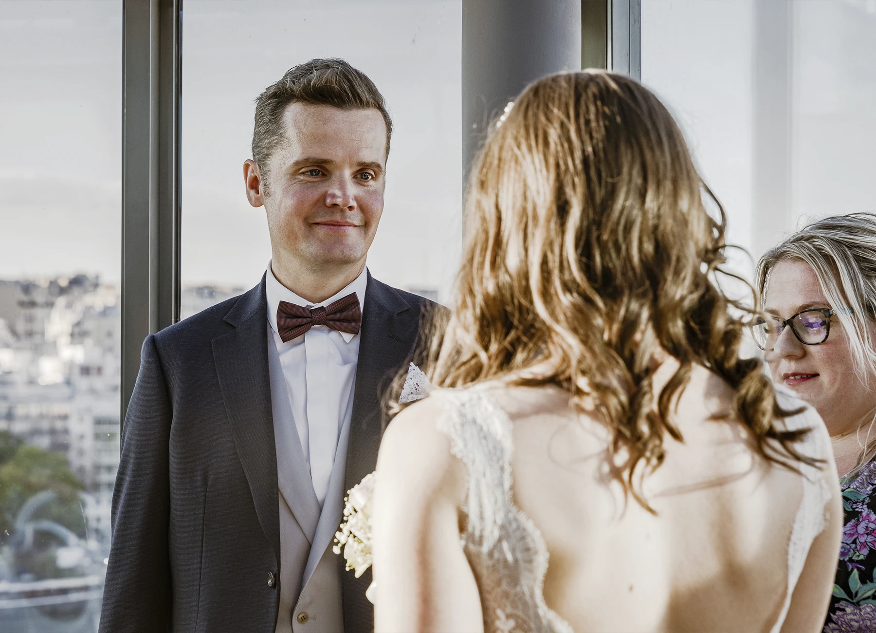 Marié souriant à sa mariée, avec celle-ci de dos en premier plan, pendant l'office laïque au Rooftop Grenelle à Paris, capturé par Laurène Zabary