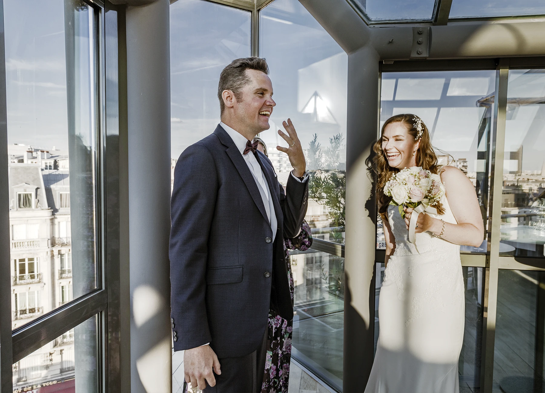 Marié montrant son alliance à l'assemblée avec un grand sourire, tandis que la mariée rit, capturés au Rooftop Grenelle à Paris par Laurène Zabary