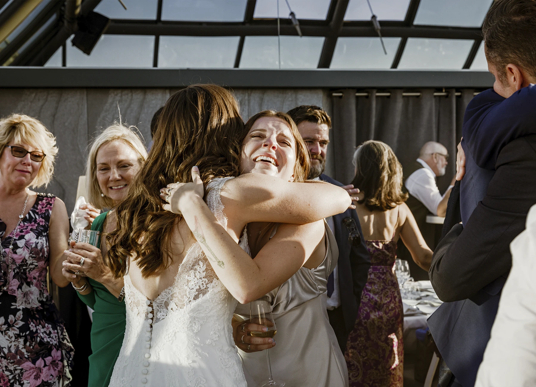 Mariée enlaçant une invitée après l'office laïque au Rooftop Grenelle à Paris, capturée par Laurène Zabary.