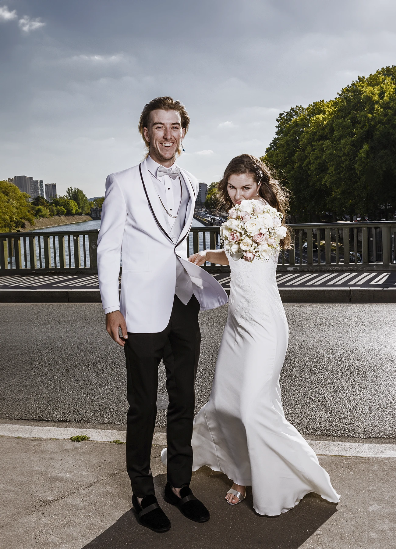 Mariée utilisant son bouquet comme épée pour une photo humoristique avec son frère sur le pont Bir Hakeim à Paris, capturée par Laurène Zabary.