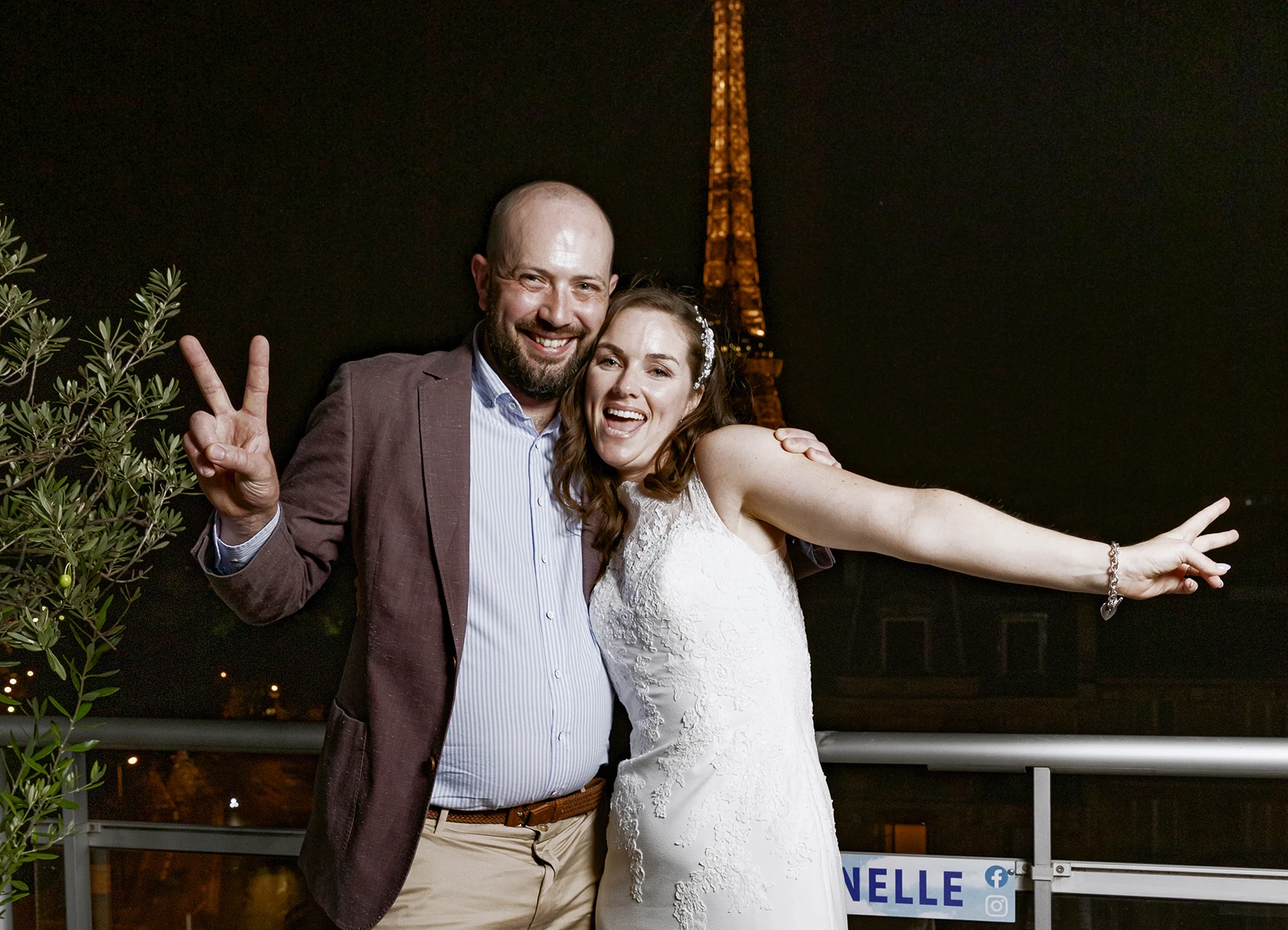 Mariée et invité posant ensemble sur le rooftop avec la tour Eiffel illuminée en arrière-plan, capturés par Laurène Zabary, photographe de mariage à Paris.