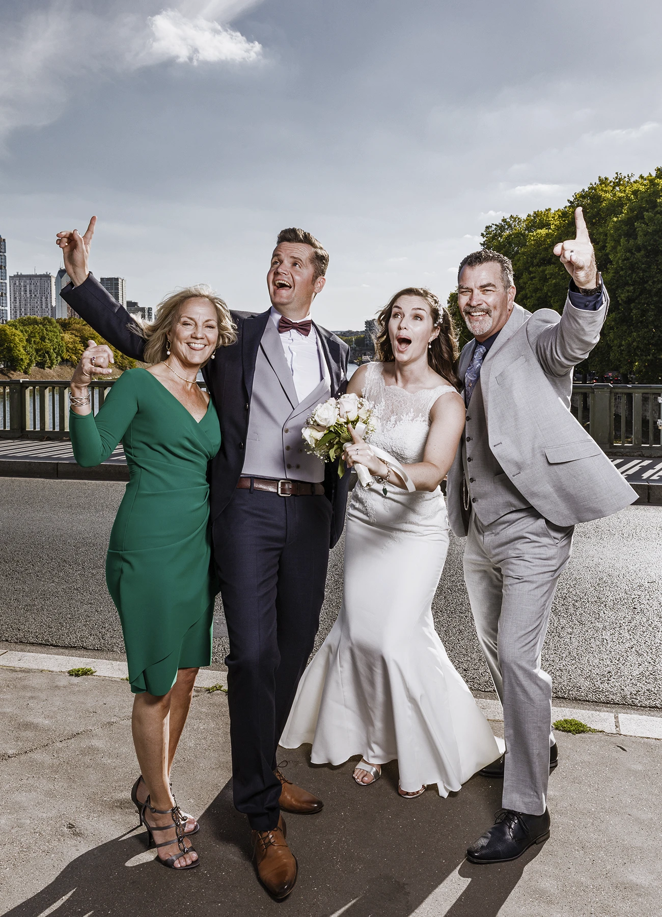 Mariés et parents posant pour une photo de groupe dynamique sur le pont Bir Hakeim à Paris, capturés par Laurène Zabary