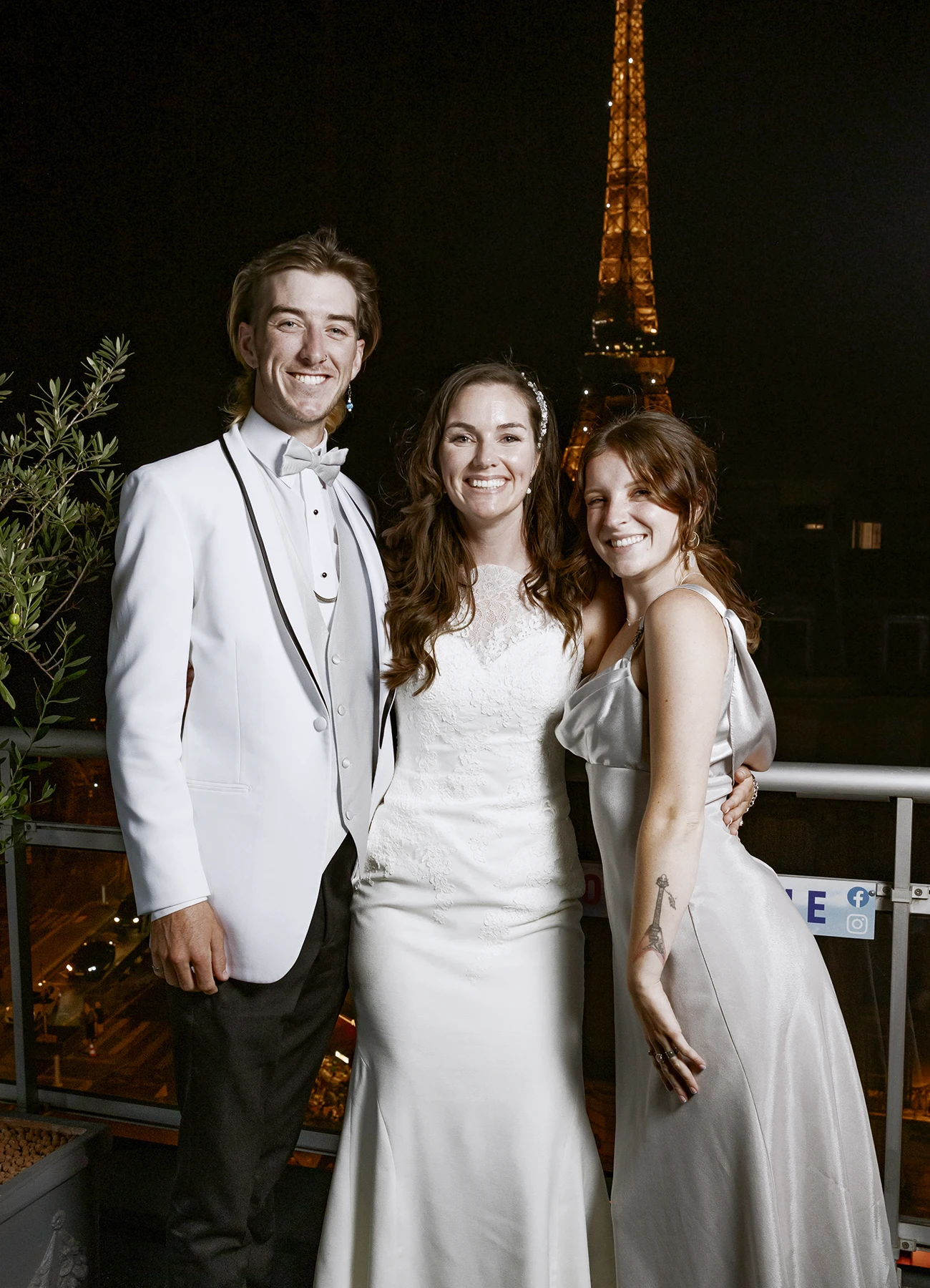 Mariée et deux invités posant sur le rooftop avec la tour Eiffel en arrière-plan, capturés par Laurène Zabary, photographe de mariage à Paris