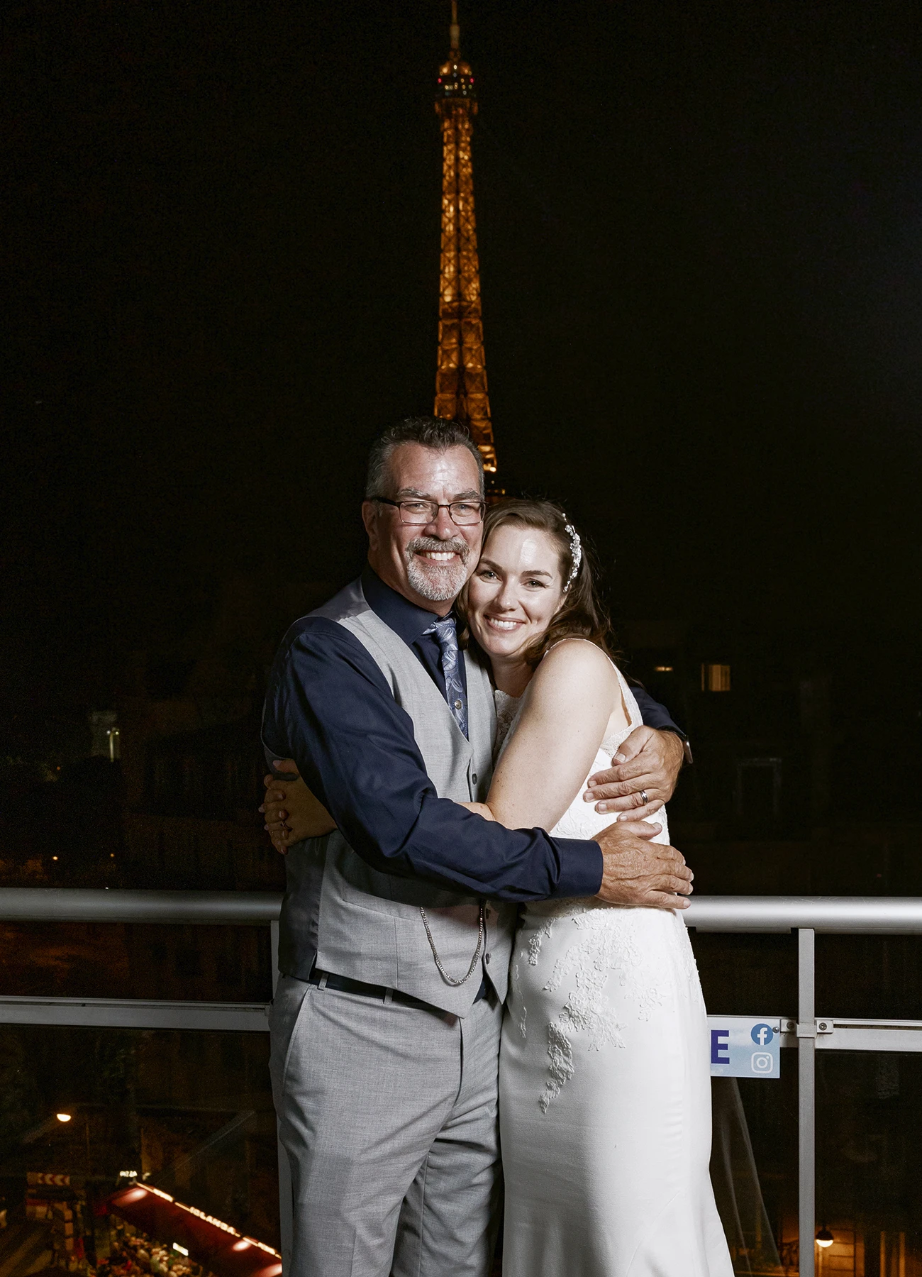 La mariée dans les bras de son père sur le rooftop avec la tour Eiffel illuminée en arrière-plan, capturés par Laurène Zabary, photographe de mariage à Paris.