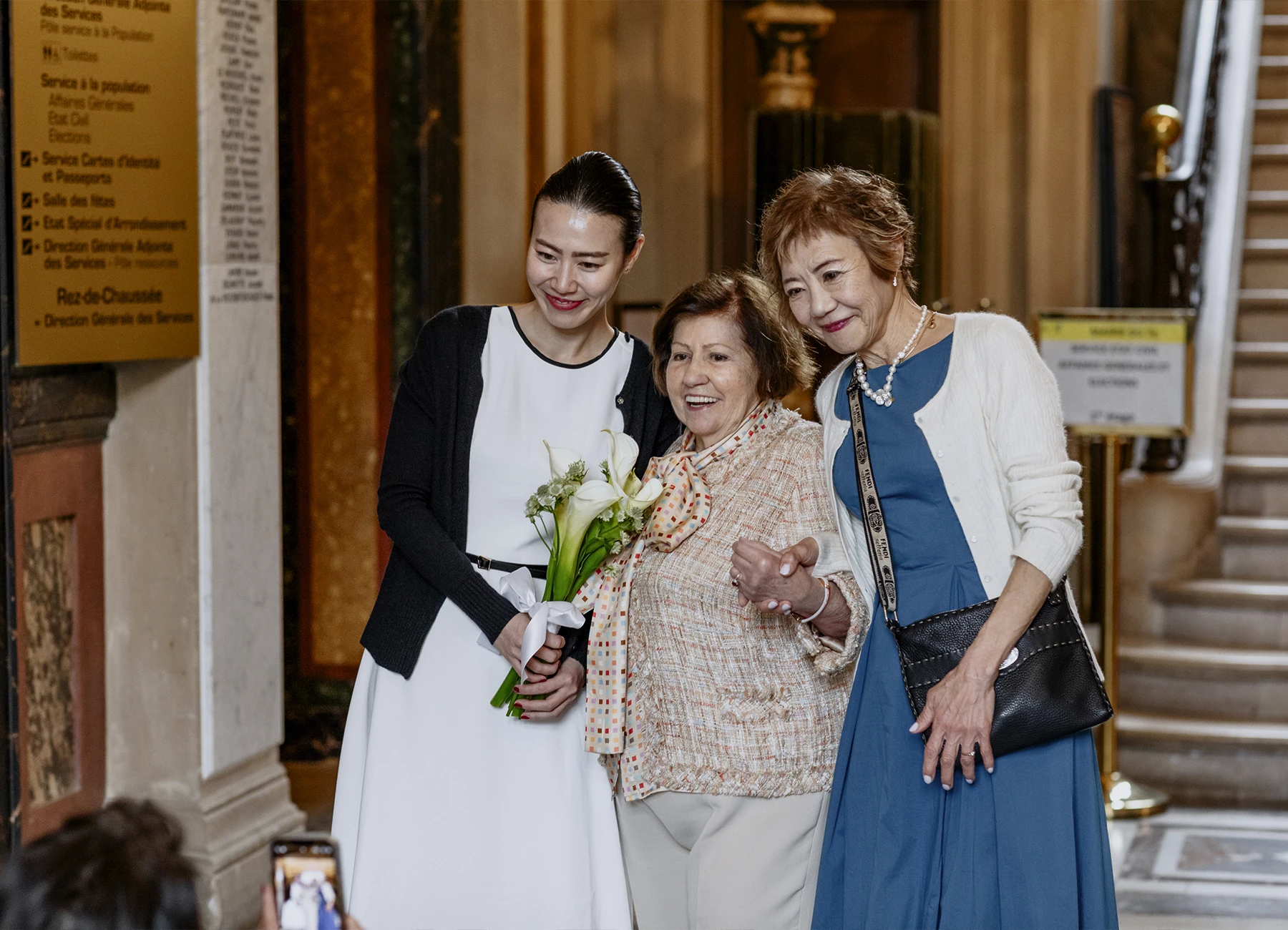 Photo de la mariée avec sa mère et la grand-mère de son futur époux, posant pour une photo prise par un invité à la mairie du 7e arrondissement