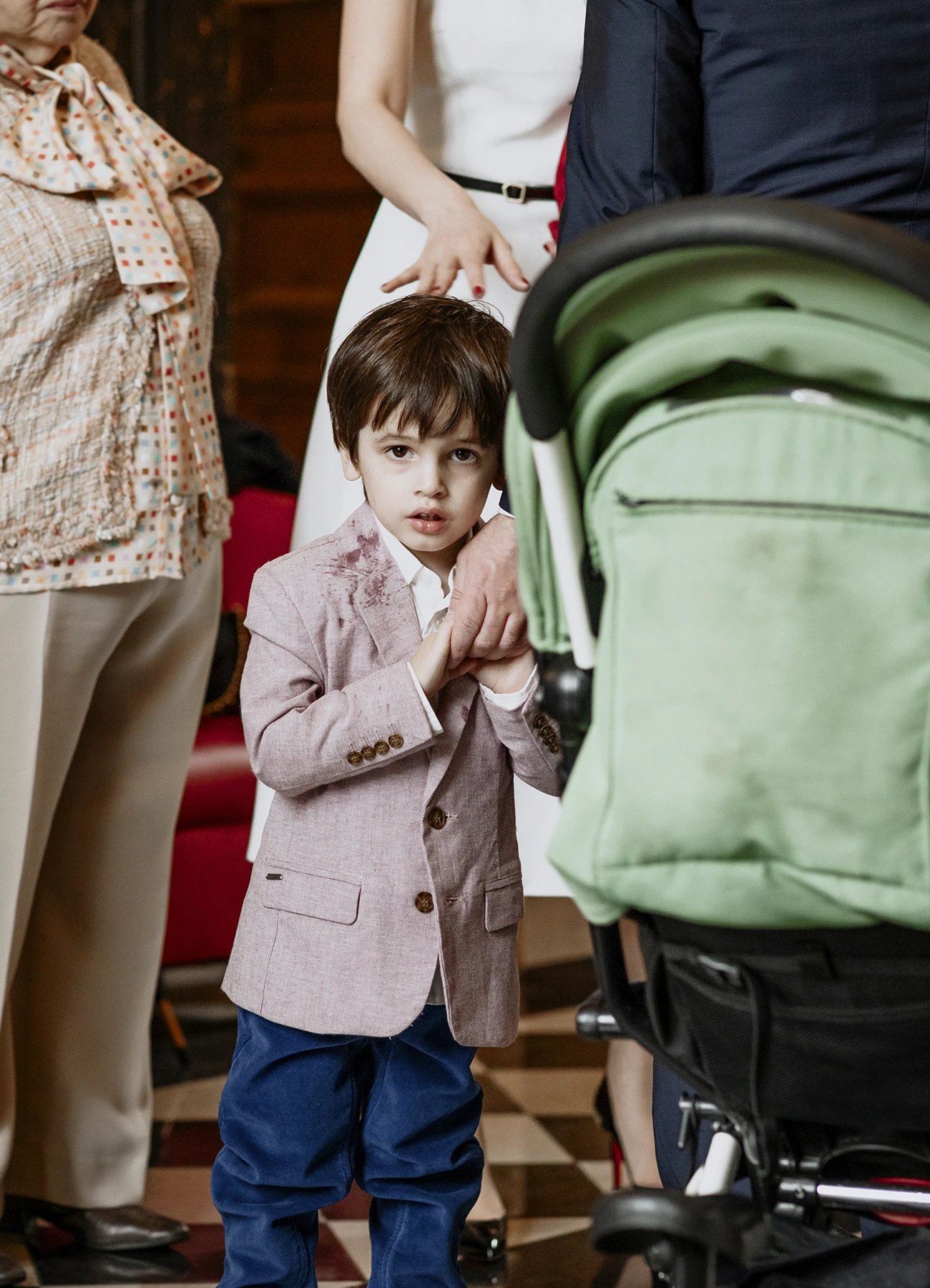 Portrait d'un petit garçon en costume bleu et rose clair souriant à la caméra lors du mariage à la mairie du 7e arrondissement