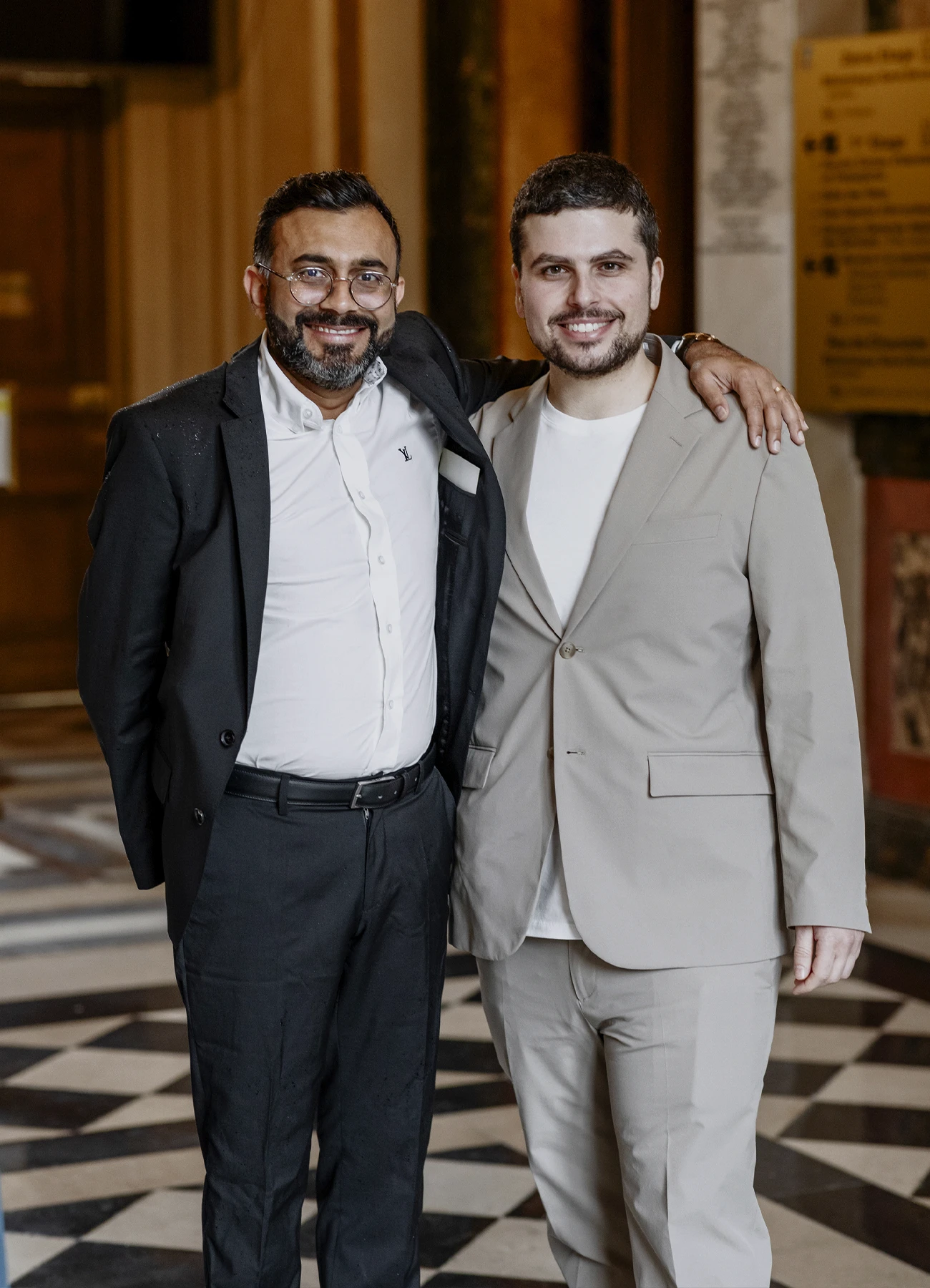 Photo du marié en costume avec son témoin à la mairie du 7e arrondissement de Paris. Le témoin a sa main sur l'épaule du marié.