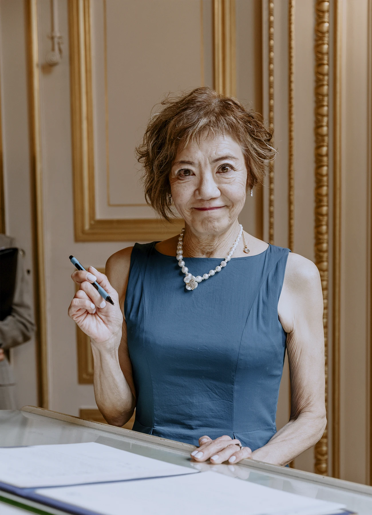 Portrait de la mère de la mariée en robe bleue tenant encore le stylo après la signature du mariage à la mairie du 7e arrondissement de Paris