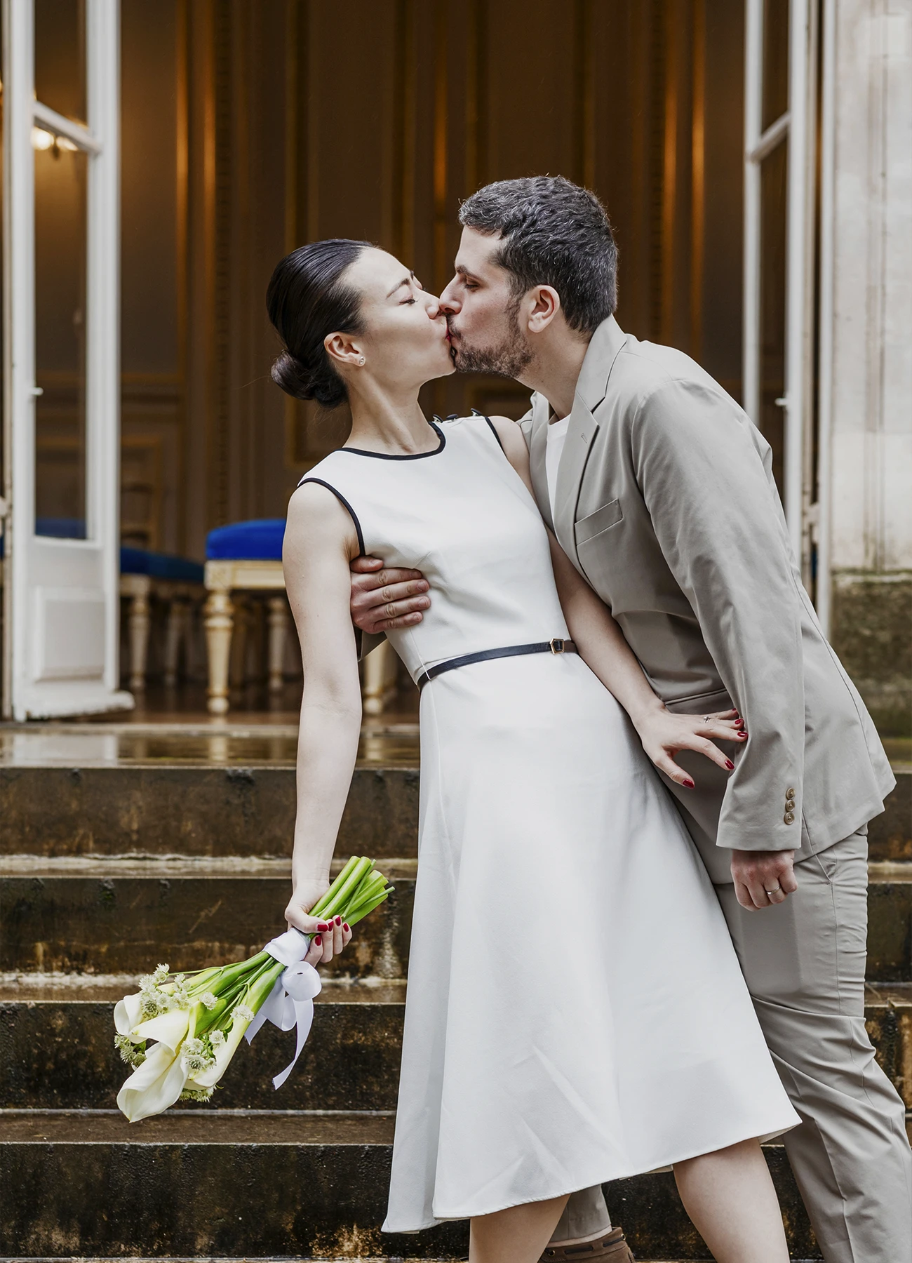 Les mariés s'embrassent sur les marches menant à la salle de mariage de la mairie du 7e arrondissement de Paris