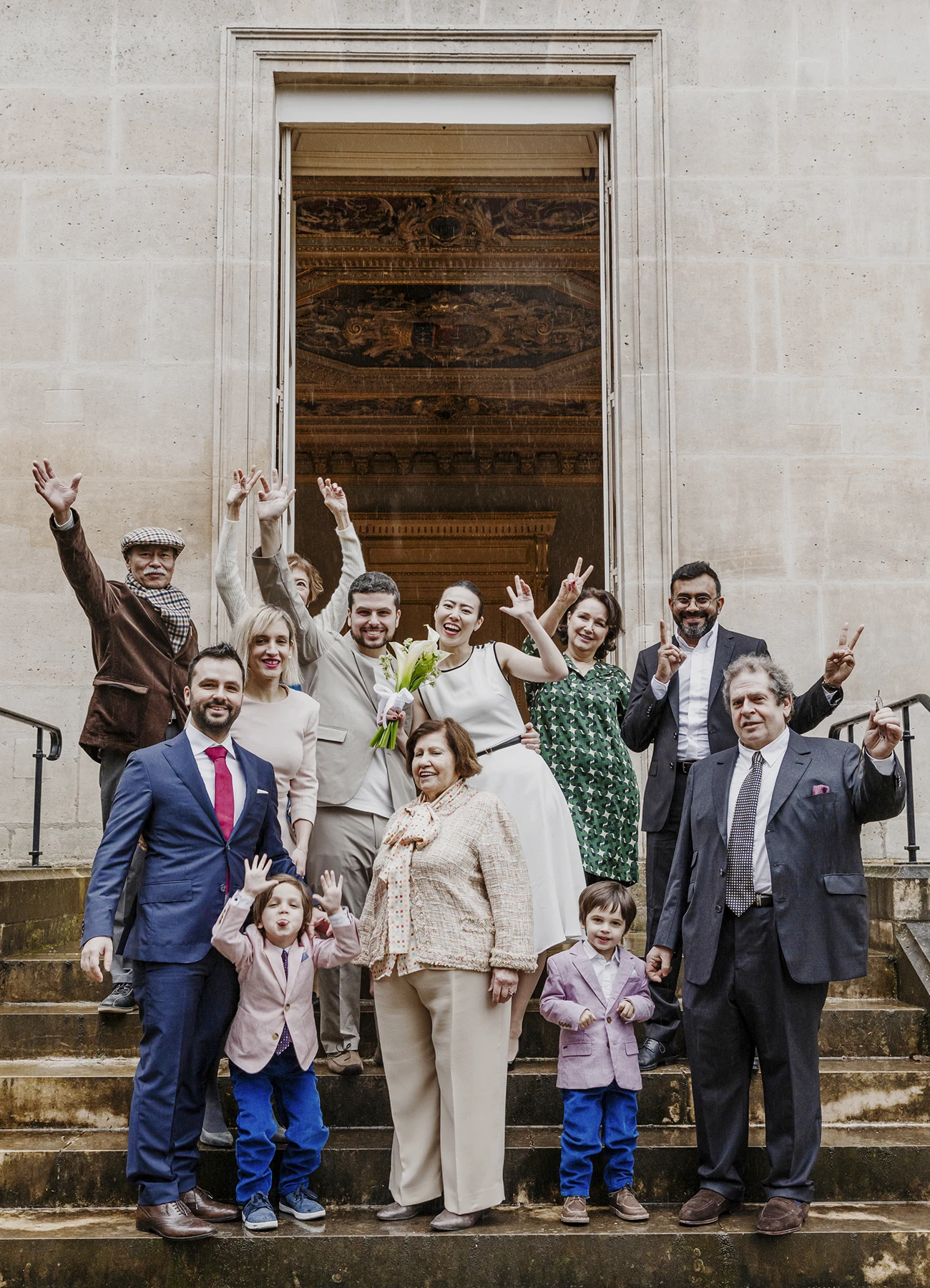 Photo de groupe avec tous les invités posant sur les marches de la mairie du 7e arrondissement de Paris après la cérémonie