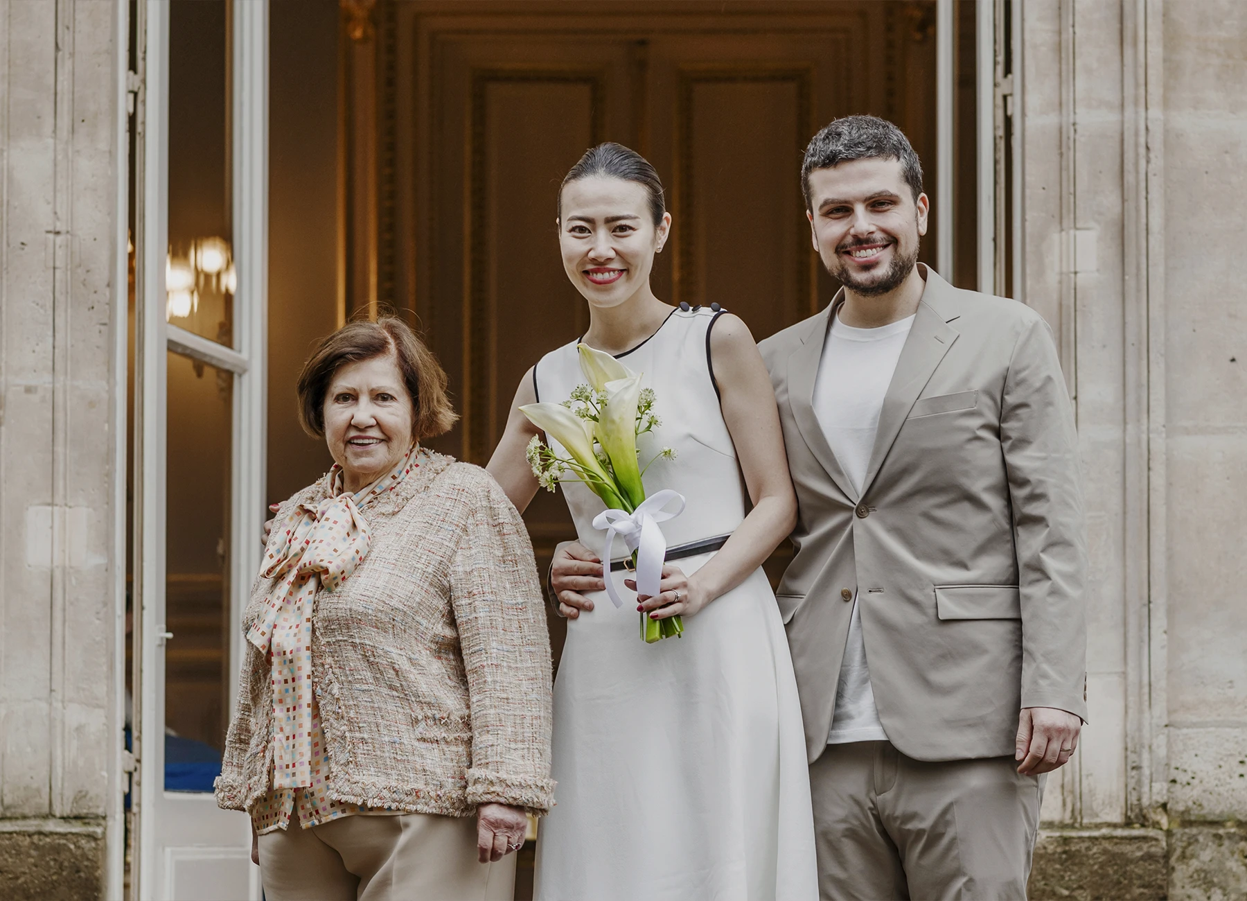 Les mariés posent avec la grand-mère sur les marches de la mairie du 7e arrondissement de Paris