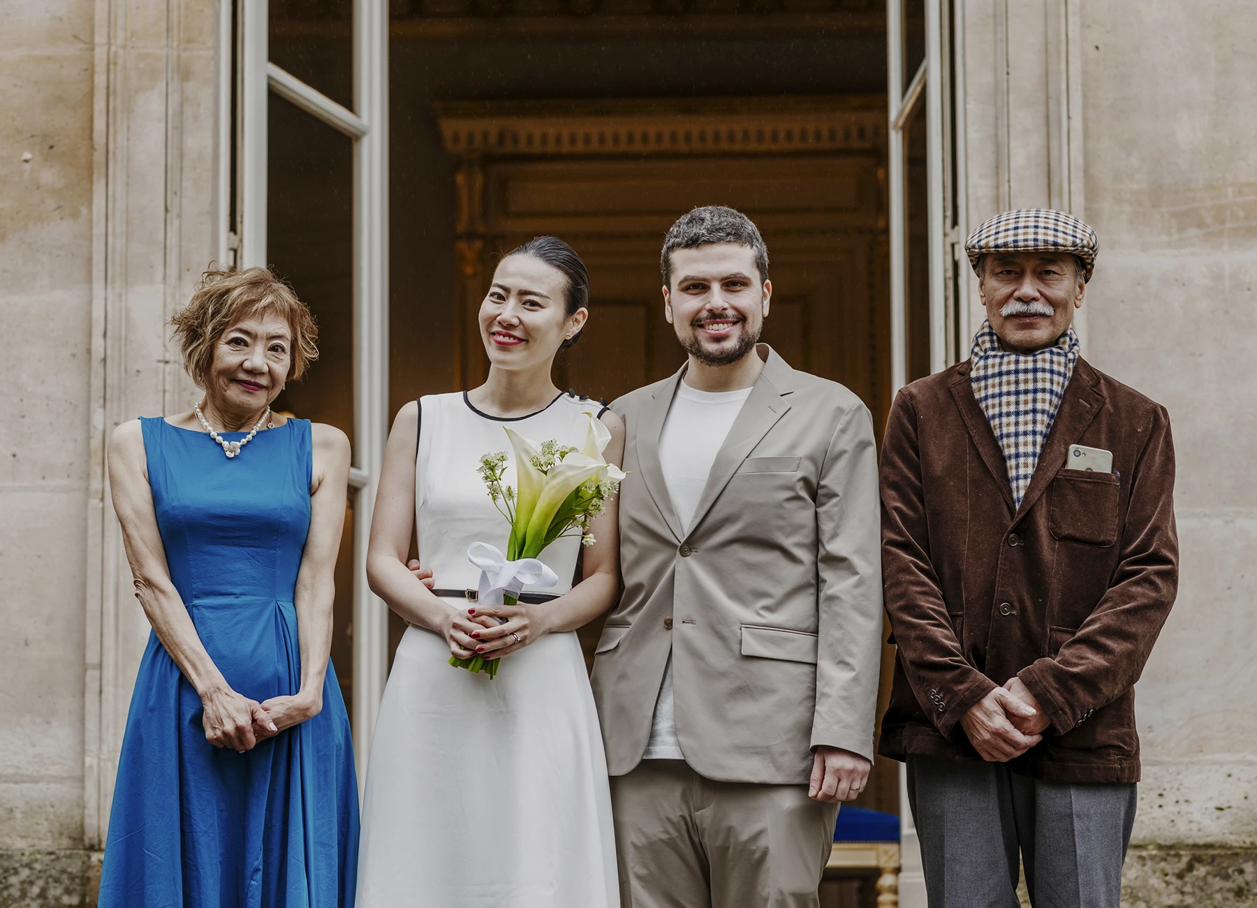 Les mariés posent avec les parents de la mariée sur les marches de la mairie du 7e arrondissement de Paris