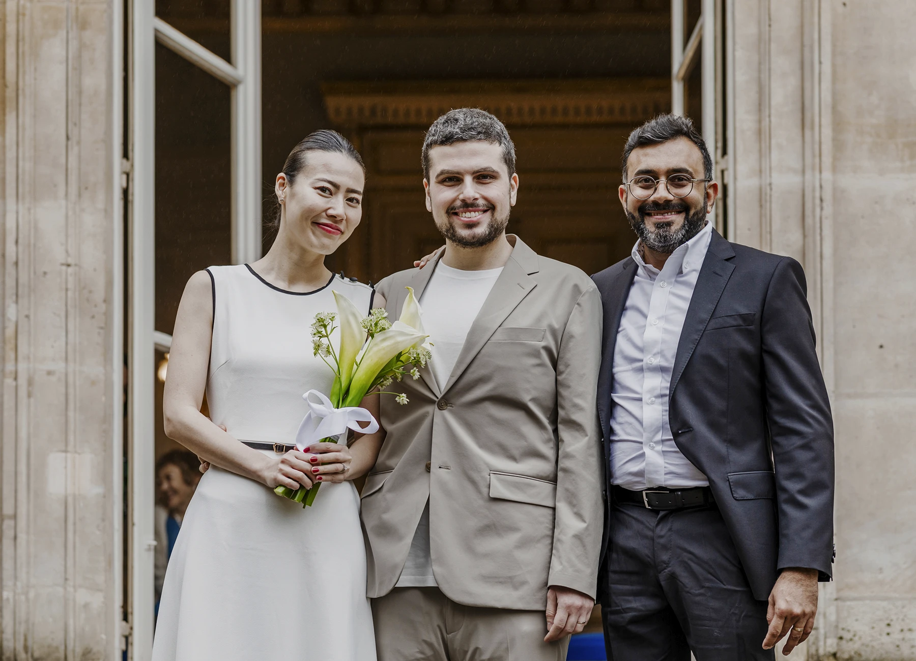 Les mariés posent avec le témoin sur les marches de la mairie du 7e arrondissement de Paris