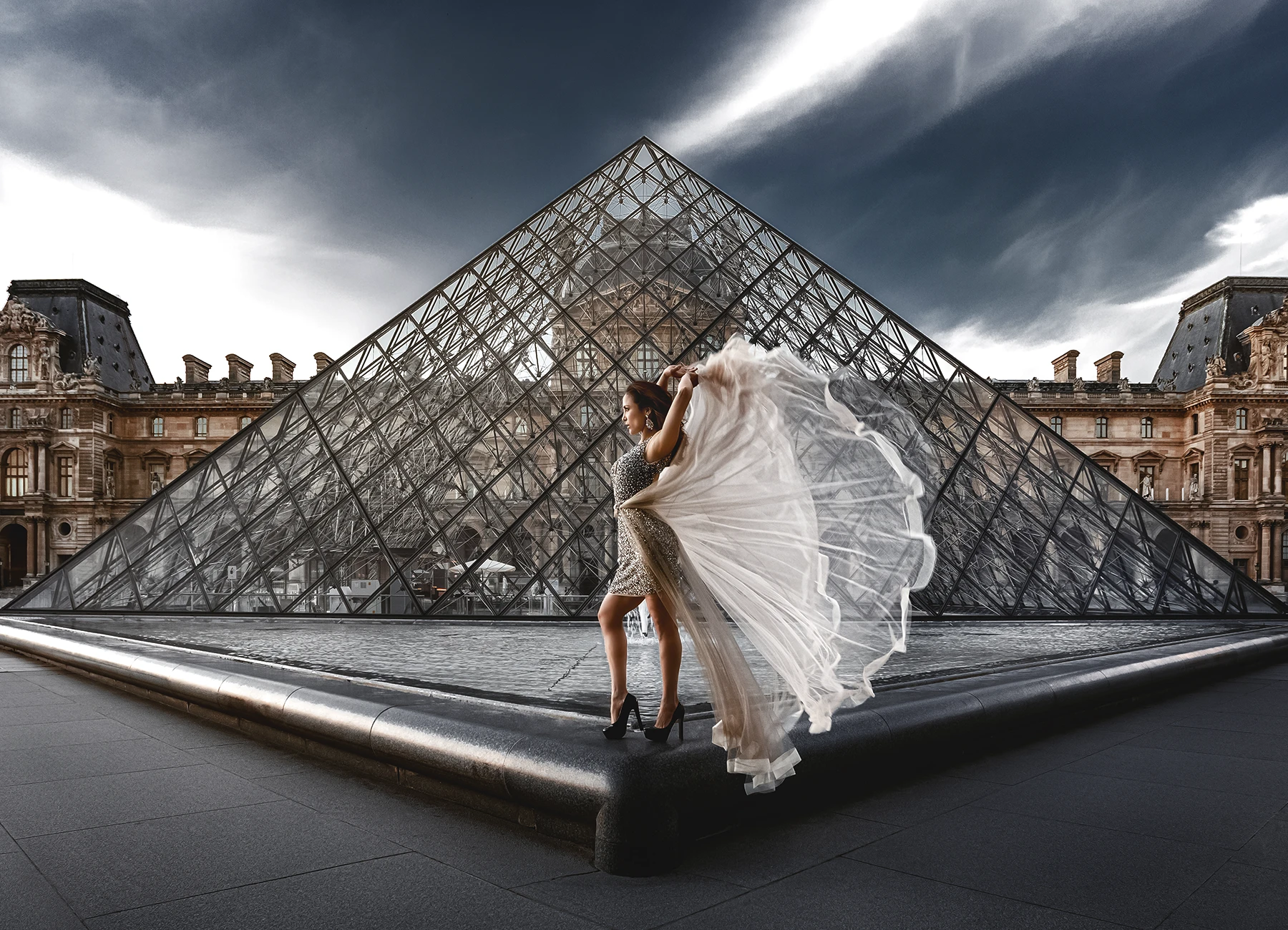 Maryluz Garcia en robe Elyssa Couture Paris devant la pyramide du Louvre. Photo de mode par Laurène Zabary.