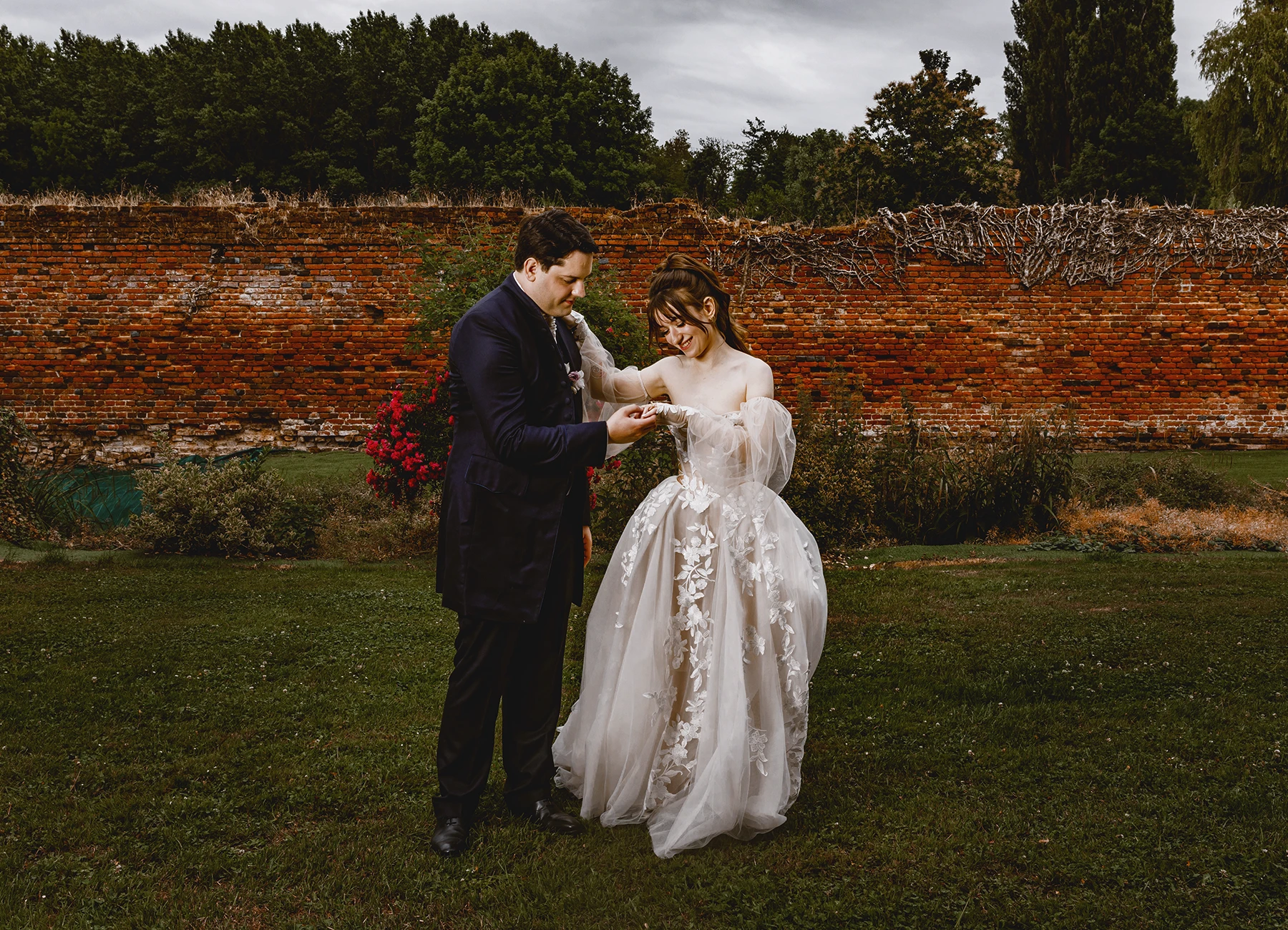 Mariés dansant ensemble devant un mur de briques lors d'un shooting de groupe en extérieur à Quesmy, photo par Laurène Zabary