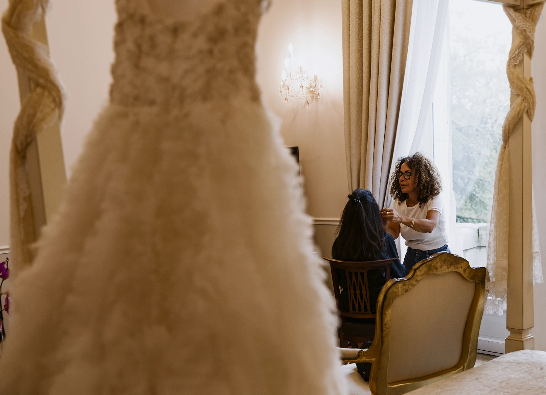 Future mariée de dos, se faisant maquiller, avec sa robe de mariage en premier plan. Photo prise par Laurène Zabary.