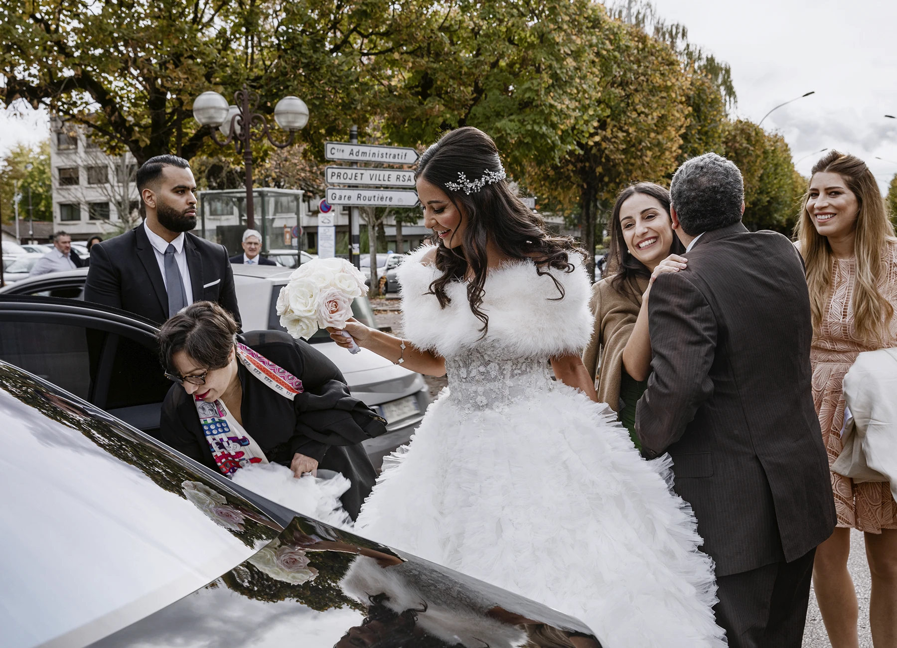 Mariée en robe blanche avec bouquet pastel, sortant de voiture à la mairie d'Aulnay-sous-Bois. Photo par Laurène Zabary