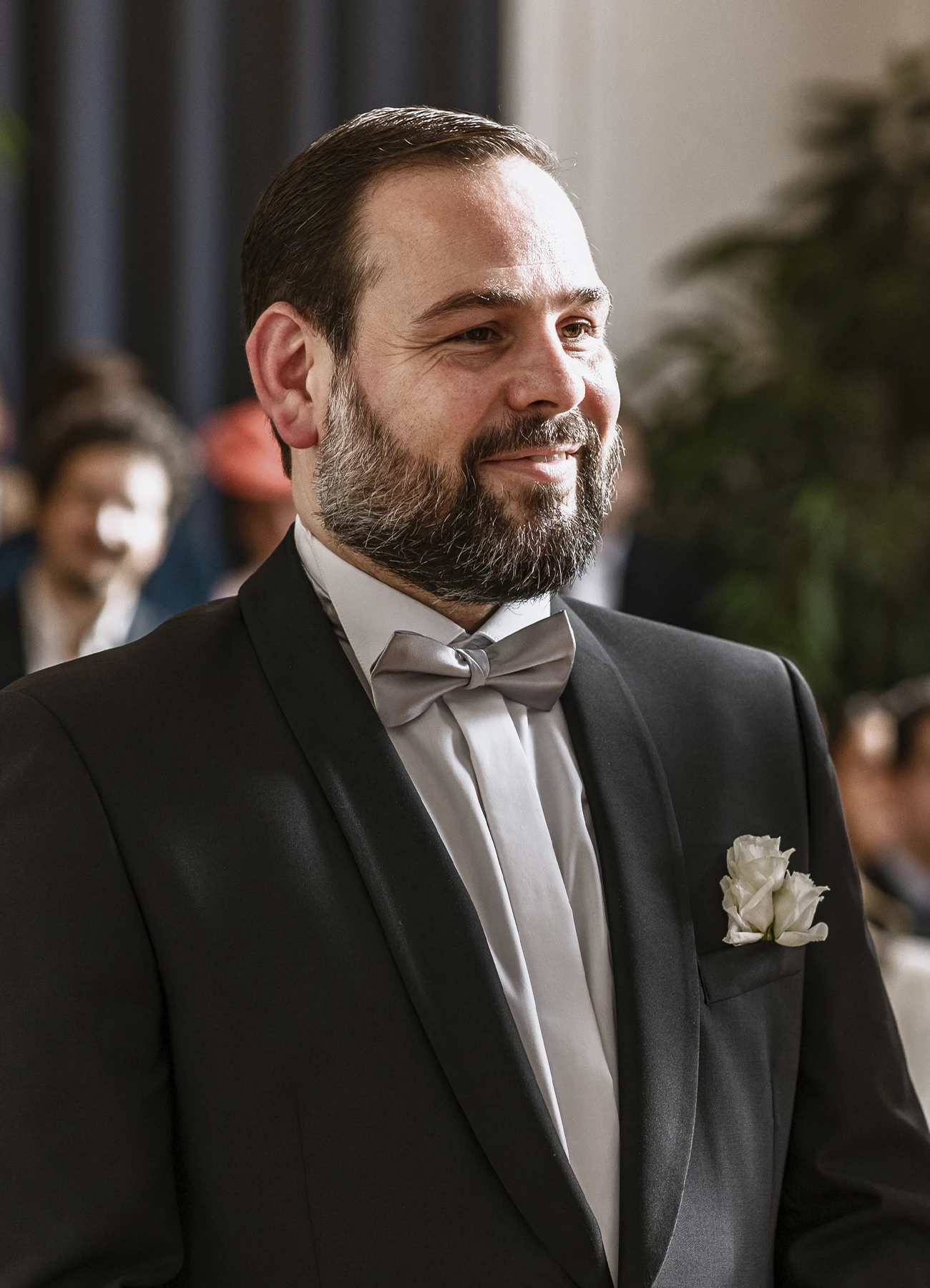 Portrait du marié en costume noir avec nœud papillon gris pendant la cérémonie. Photo par Laurène Zabary