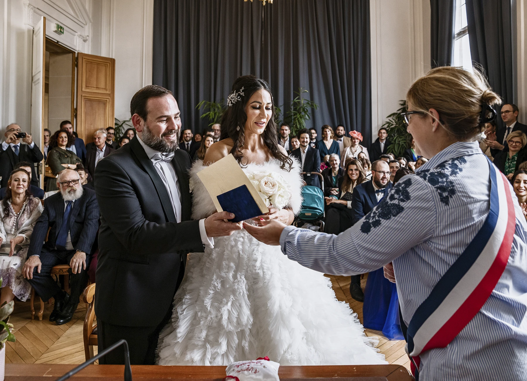 Officier d'état civil tendant le livret de famille aux mariés à la mairie. Photo par Laurène Zabary.