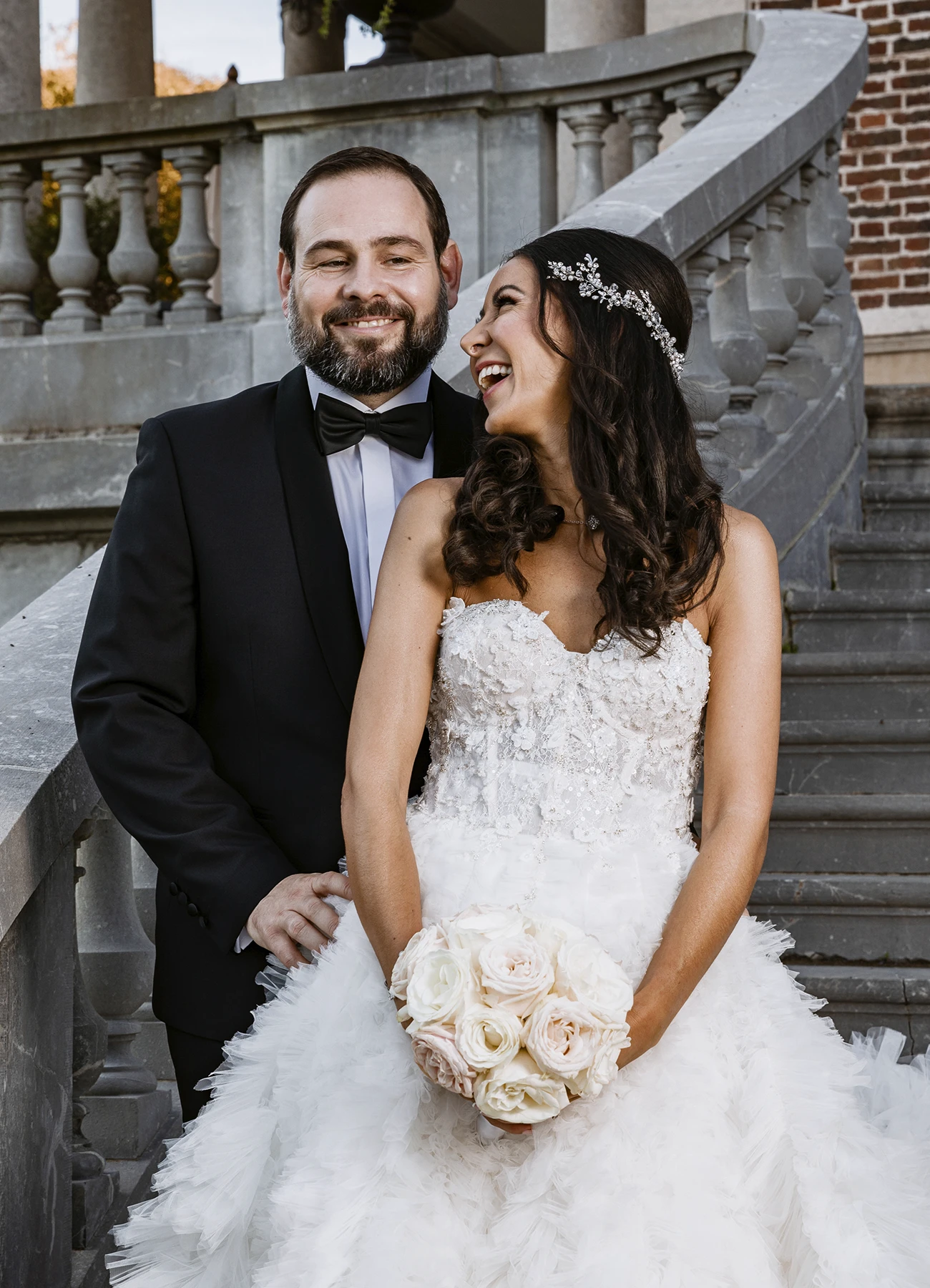 Mariée souriant à son époux sur les escaliers du Château Bouffémont. Le couple partage un moment complice sous le soleil. Photo par Laurène Zabary