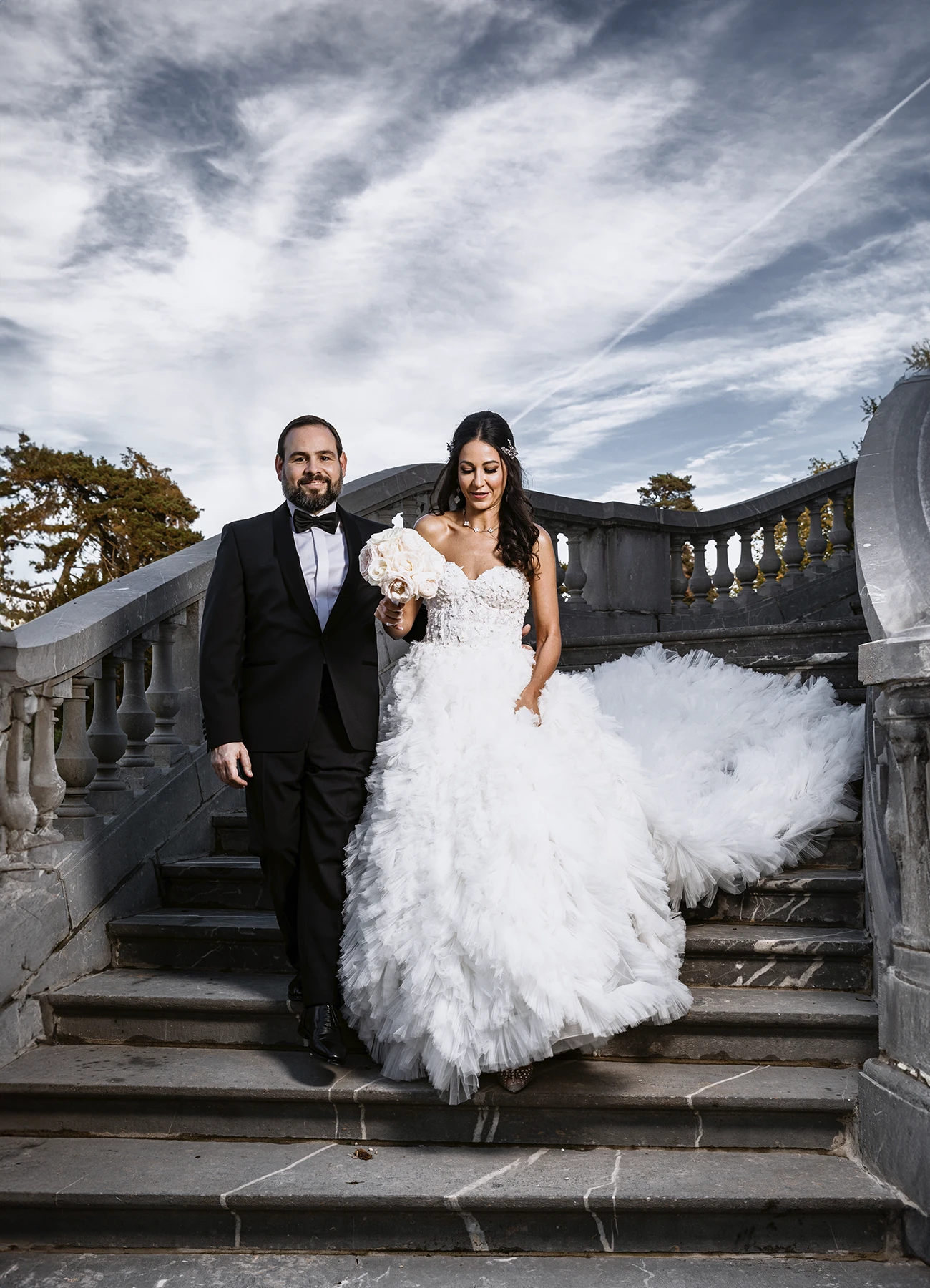 "Couple de jeunes mariés élégants sur les marches extérieures du Château Bouffémont. Photo par Laurène Zabary.