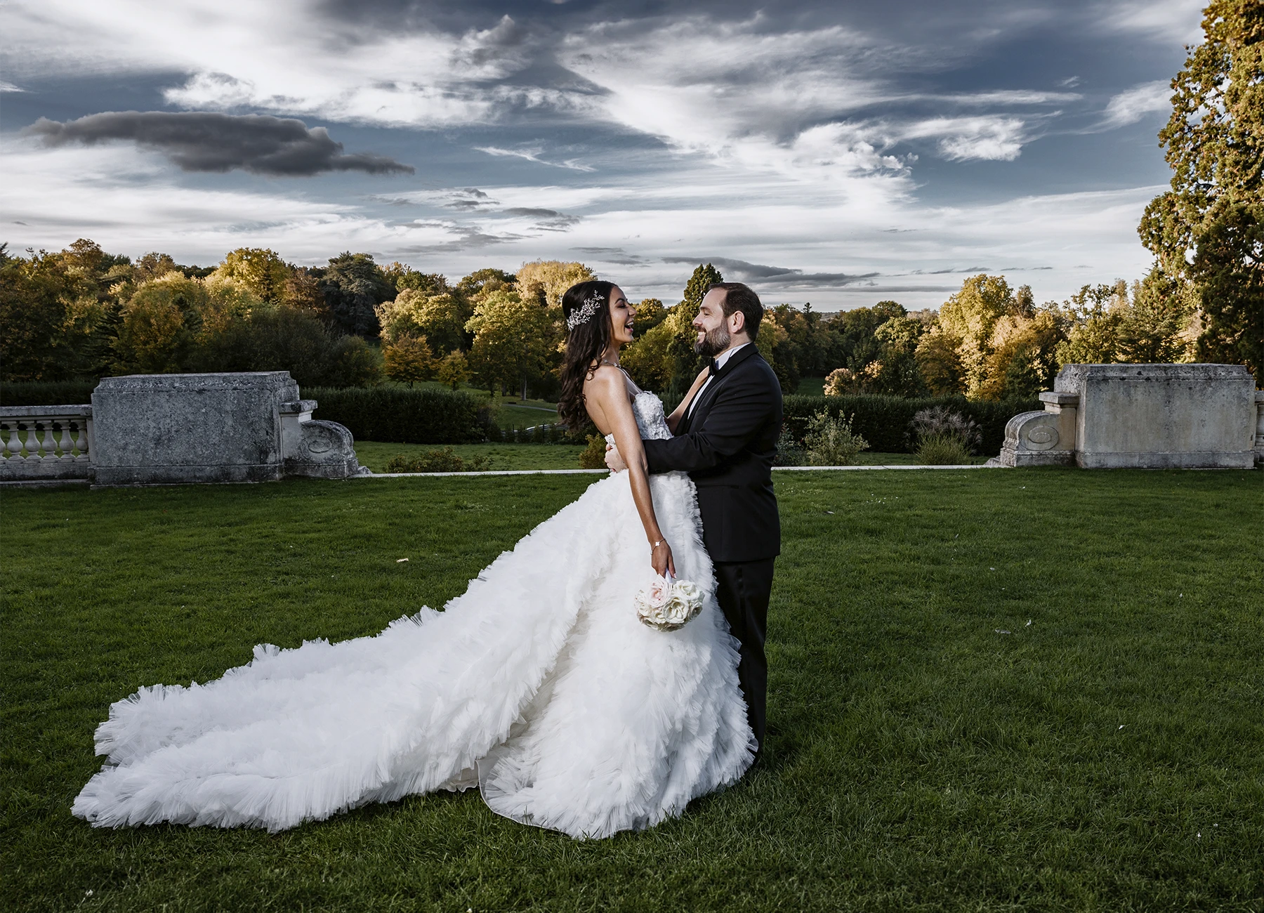 Les jeunes mariés posent ensemble devant le parc luxuriant du Château Bouffémont par un beau temps. Photo par Laurène Zabary