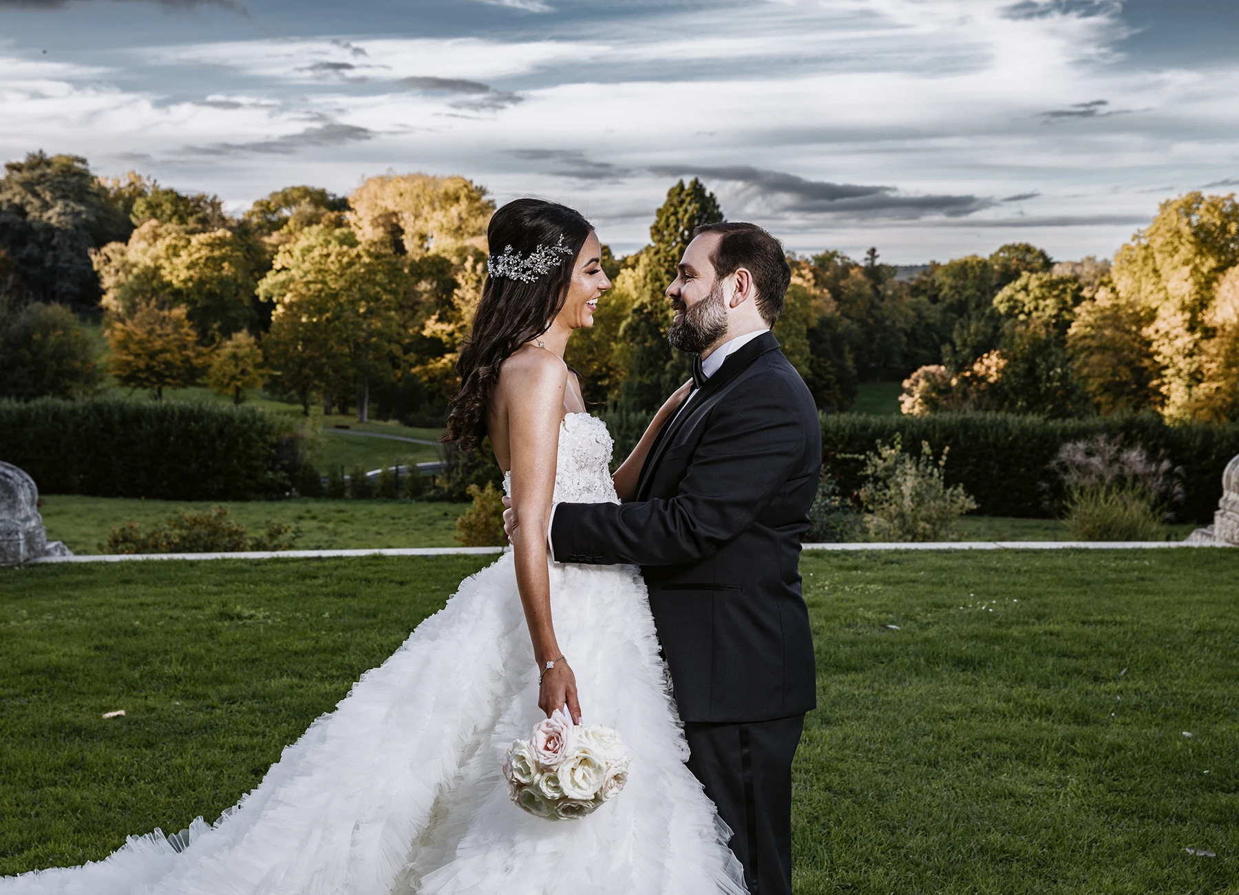 Les jeunes mariés posent ensemble devant le parc luxuriant du Château Bouffémont par un beau temps. Photo par Laurène Zabary