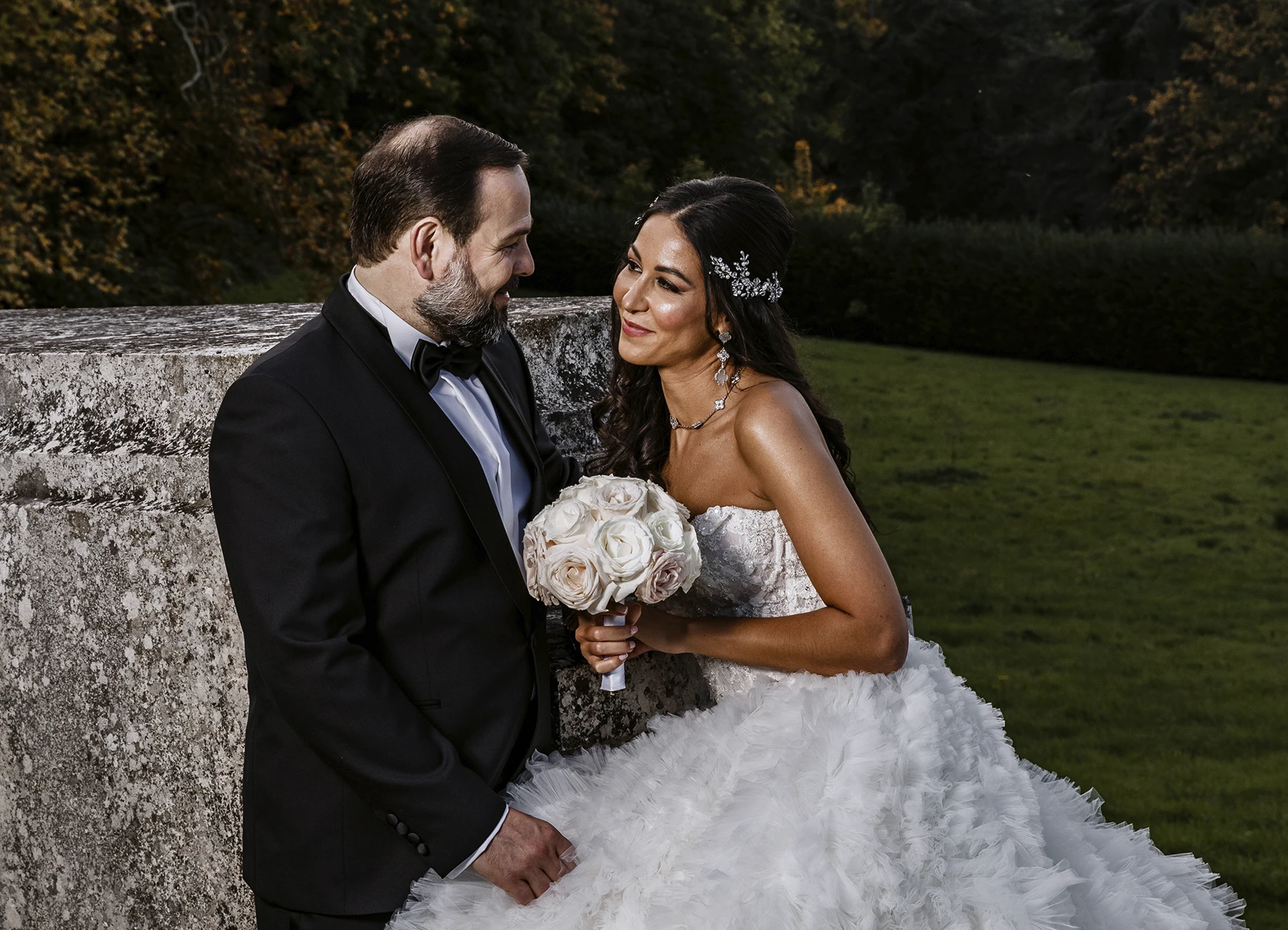 Mariés posant dans le parc du Château Bouffémont, profitant de la beauté du lieu pour leur séance photo. Photo par Laurène Zabary.